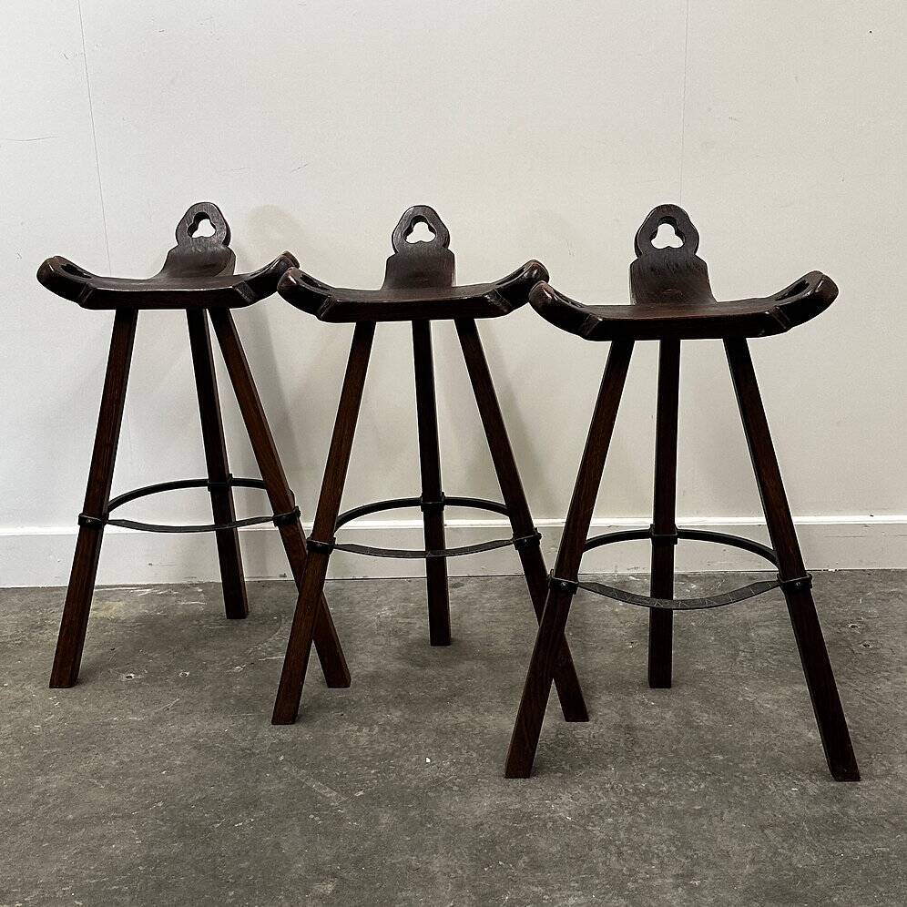 Set of 3 rustic carved oak bar stools with iron footrests, 1970s