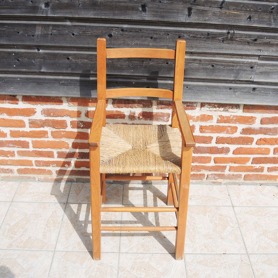 Old wooden high chair for children with straw.