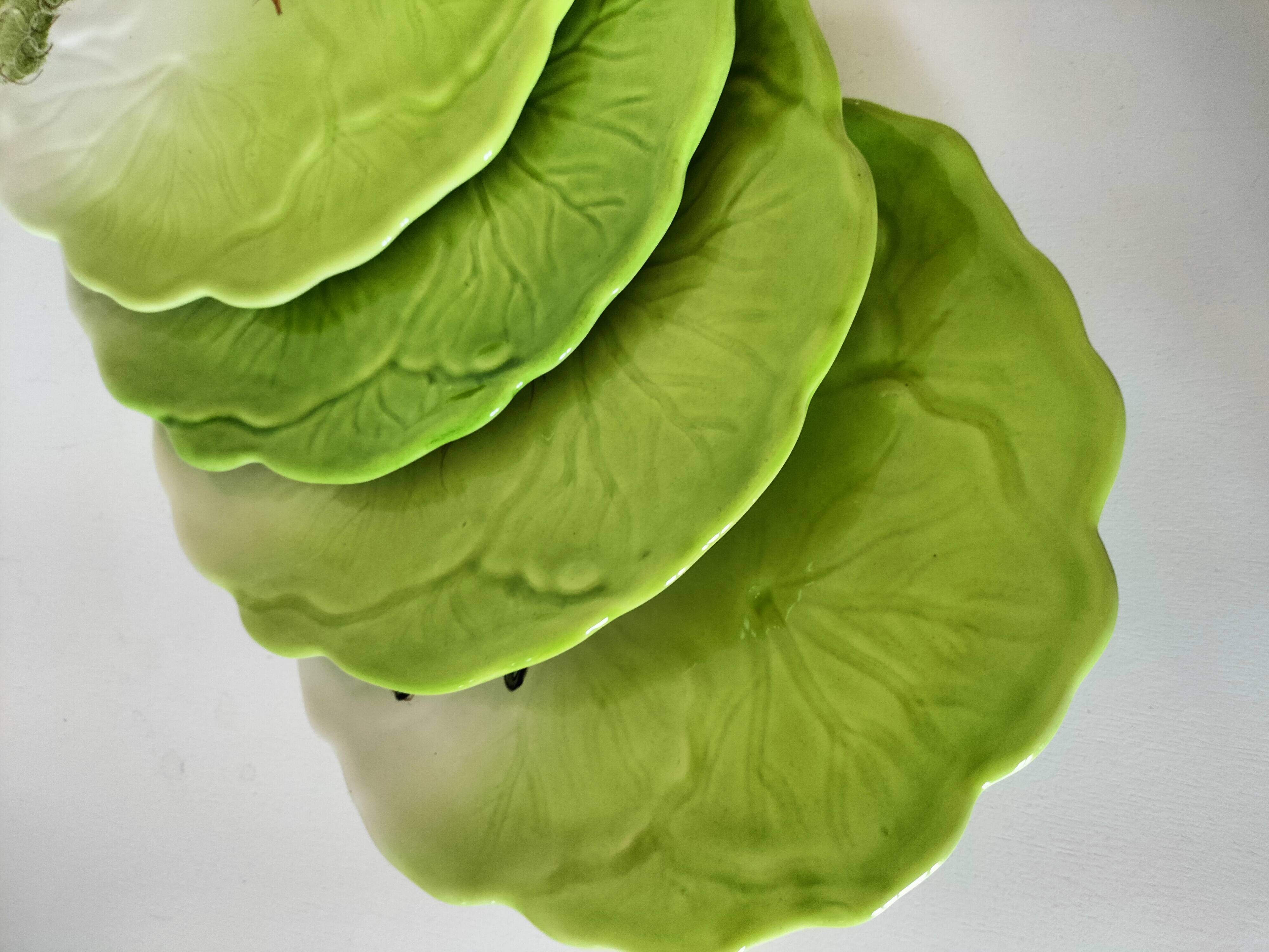 4 hand-decorated earthenware plates with vegetable and green leaf designs.