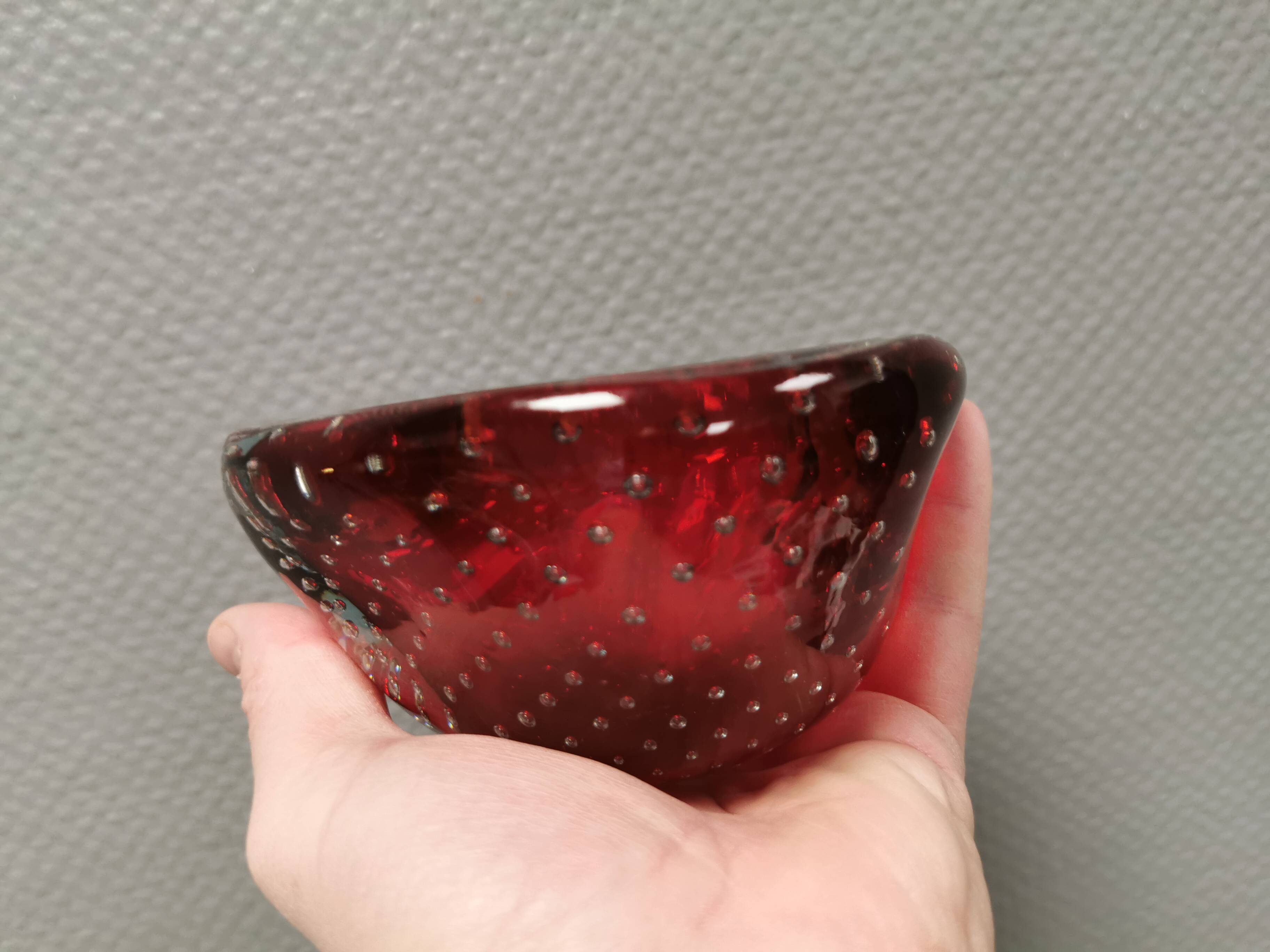 Small glass bowl in beautiful emerald red color with inlaid bubbles.