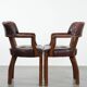 Set of two brown leather Chesterfield dining chairs in English style.