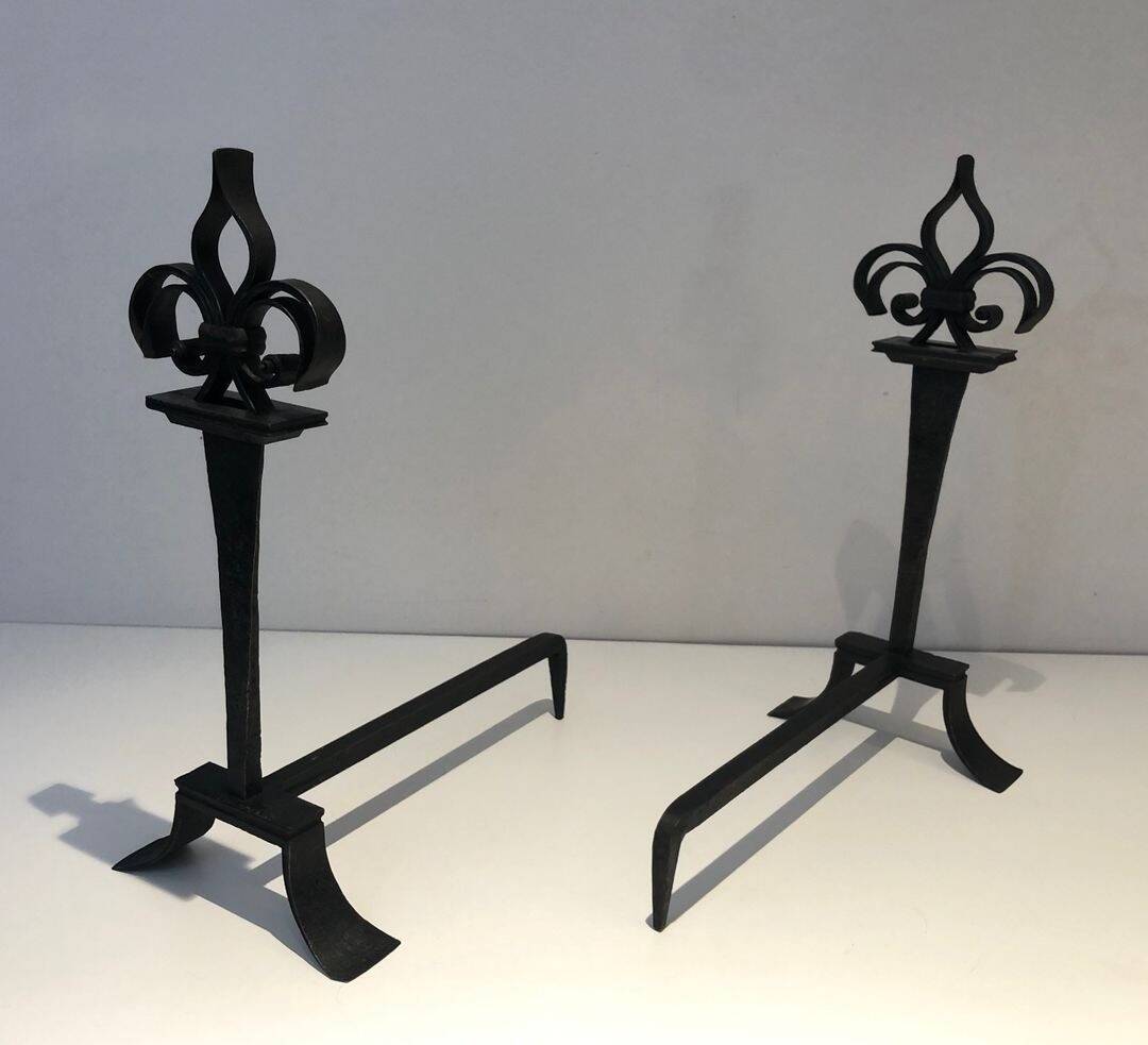 Important pair of wrought iron andirons with torch in heraldic fleur-de-lis design.