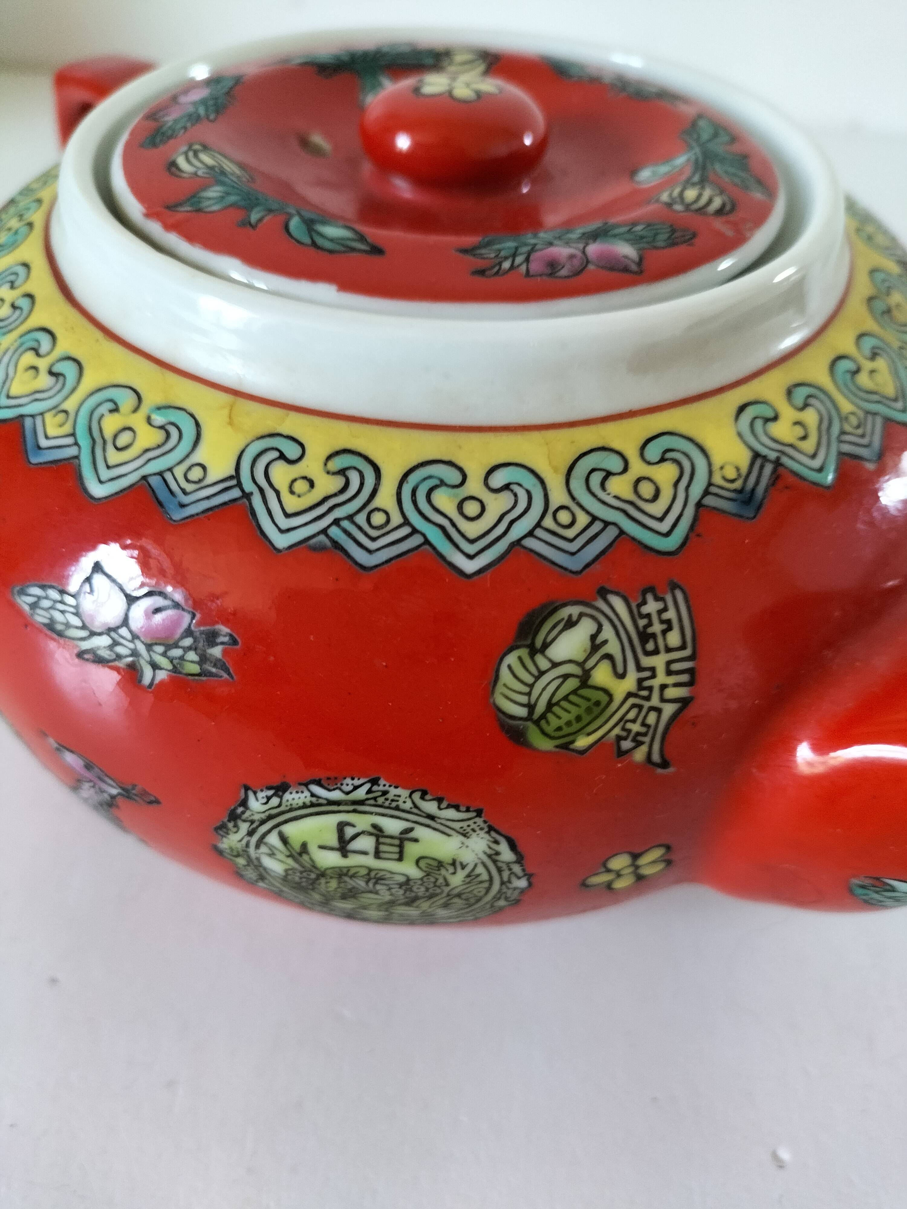 Vintage red Chinese teapot decorated with dragons and symbols.