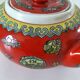 Vintage red Chinese teapot decorated with dragons and symbols.
