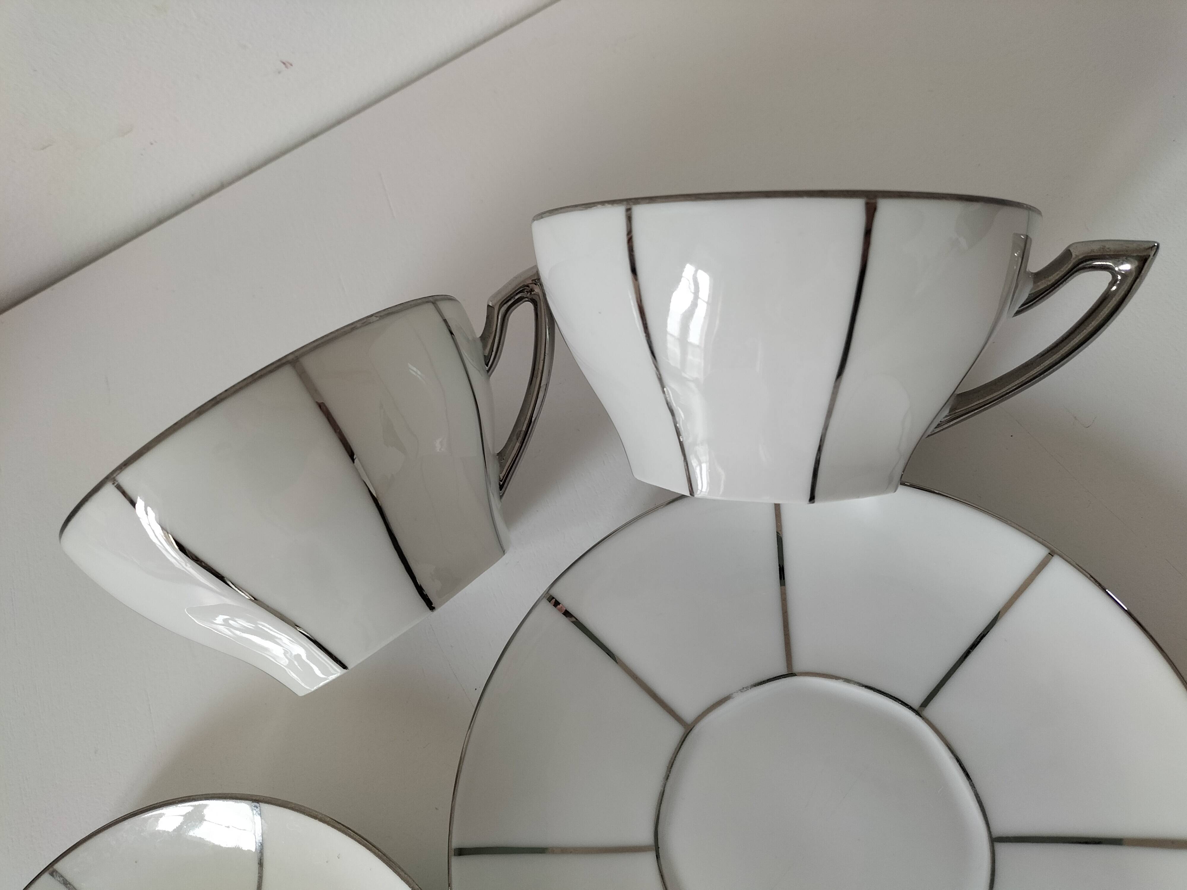 Two Art Deco porcelain cups and saucers with silver trim.