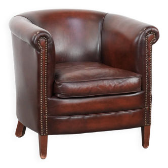 Fauteuil club en cuir de vache bien entretenu dans une couleur rouge/marron luxueuse.