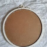 Round mirror in carved wood with at the top a ribbon forming a knot in cream color