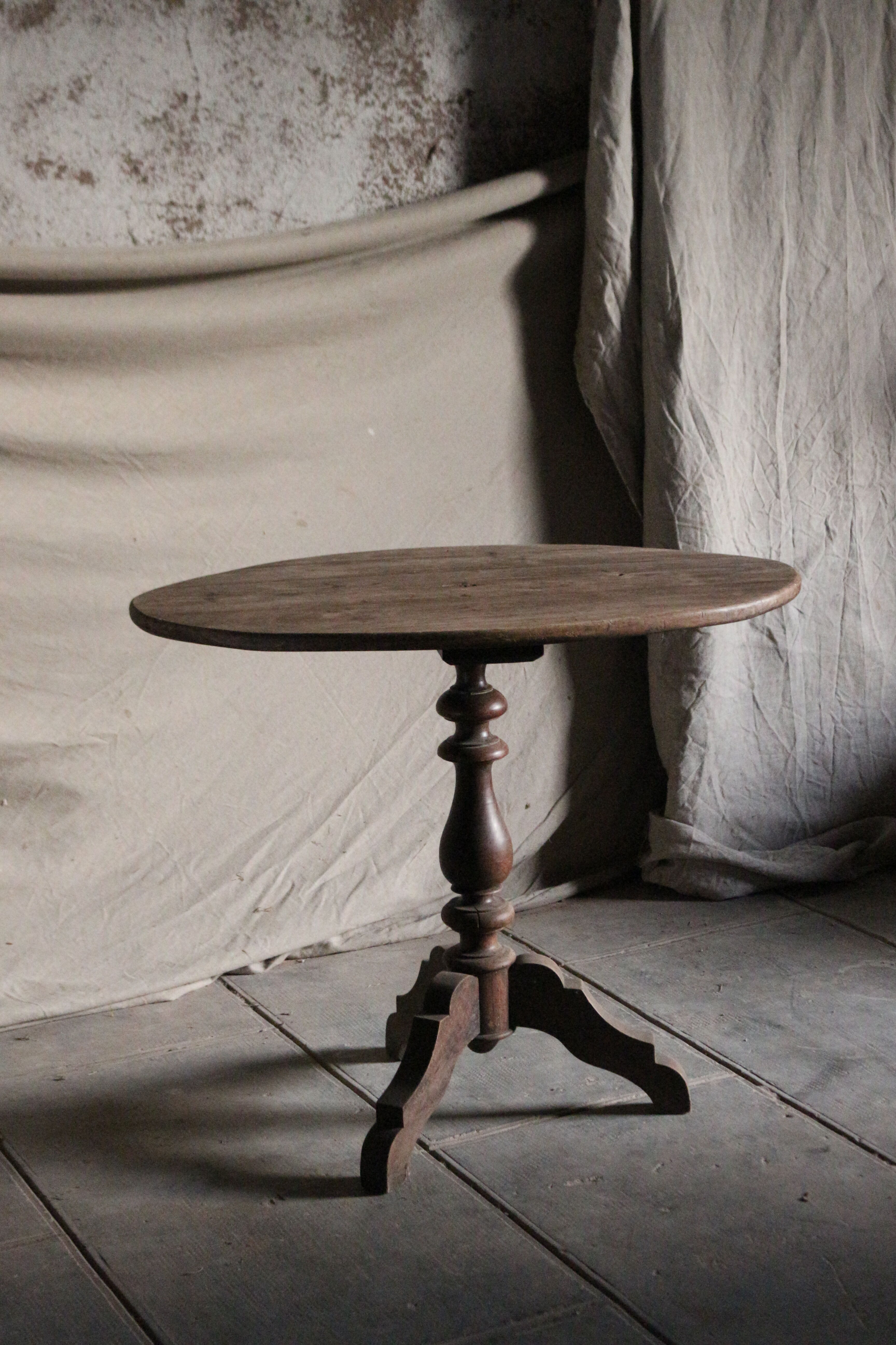 Old oval pedestal table in raw wood