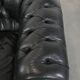 Ensemble composé d'un canapé chesterfield noir, d'un fauteuil et d'un pouf.
