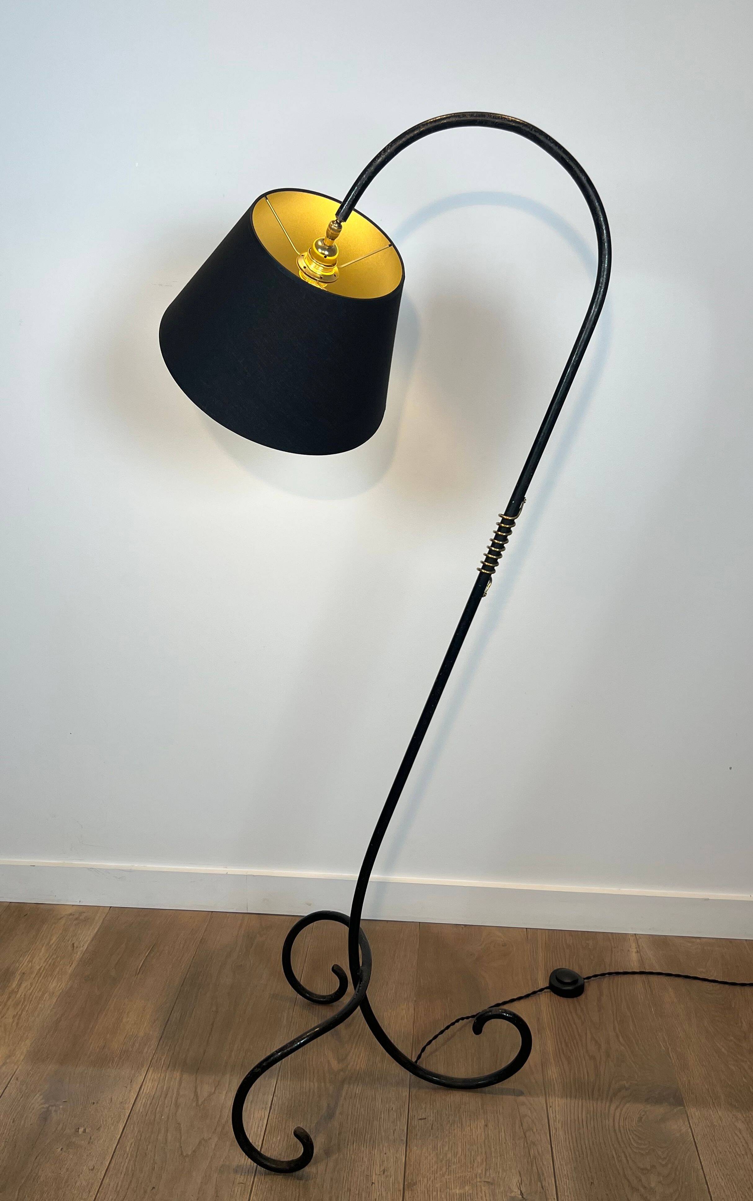 Design floor lamp in black lacquered metal and brass.