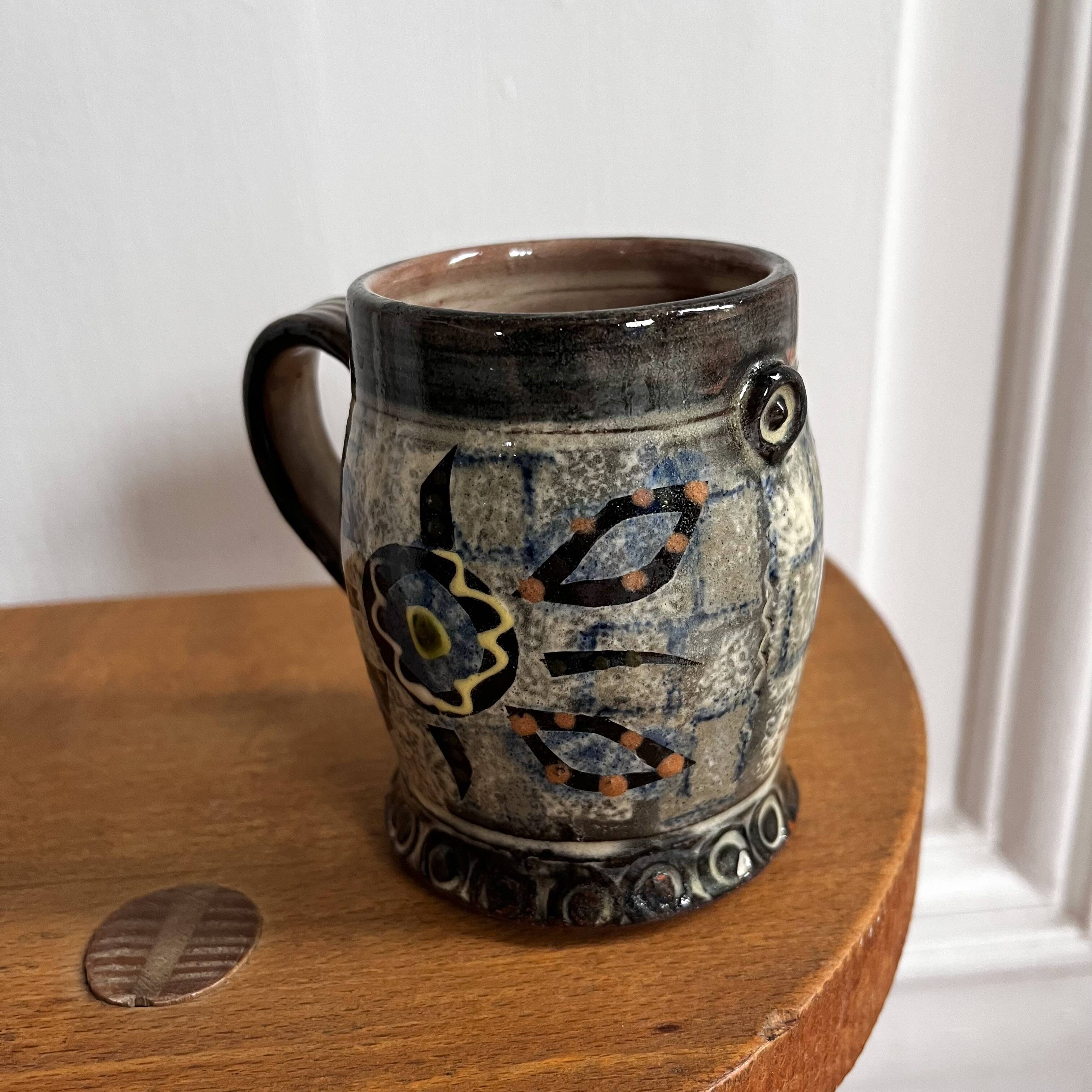 Vintage terracotta mugs with glazed designs and flower/fish motifs