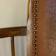 Antique armchair in solid wood and patinated brown leather, early 20th century.