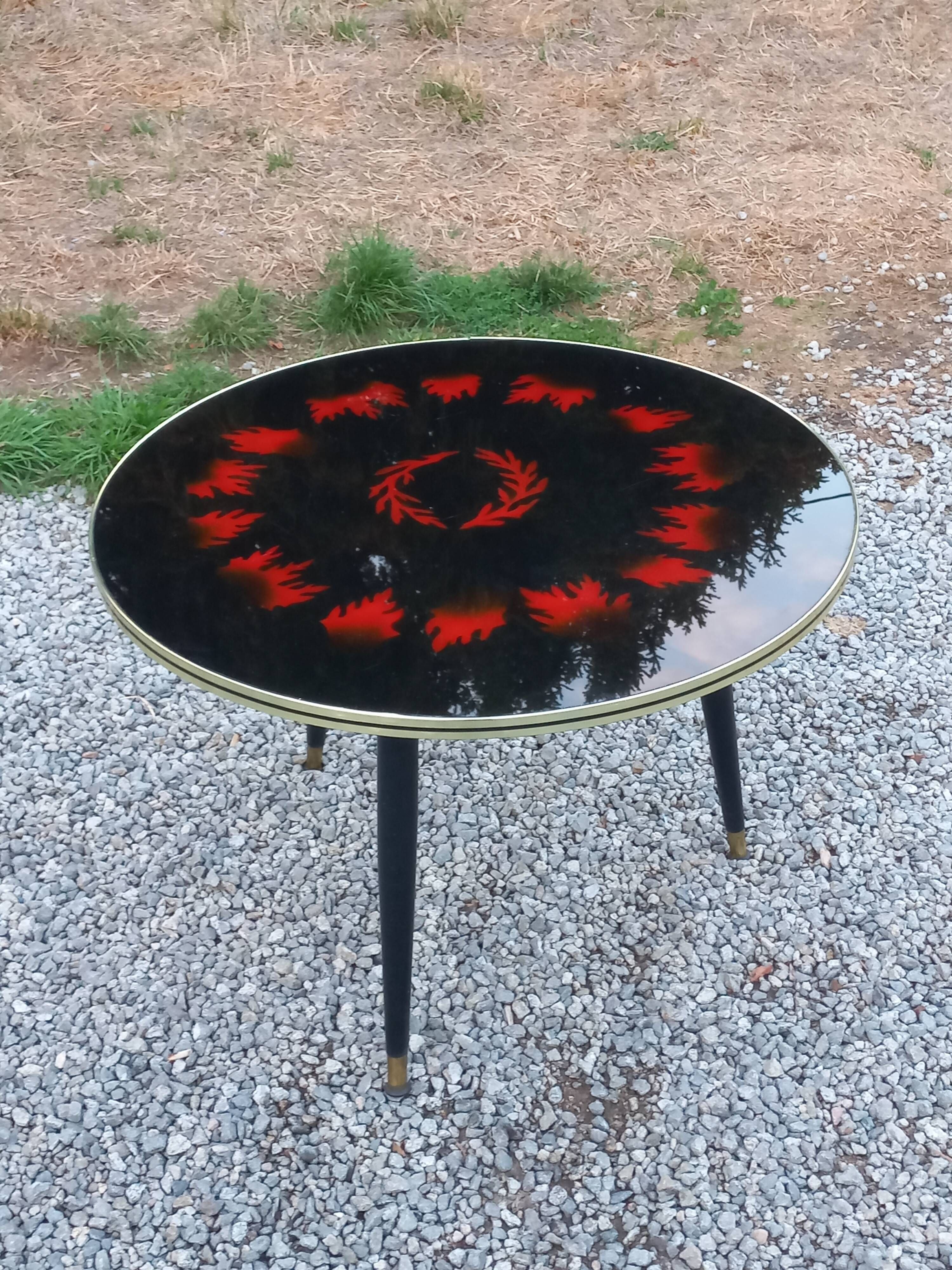 Vintage coffee table with glass top and tripod legs in blackened wood from the 1960s.