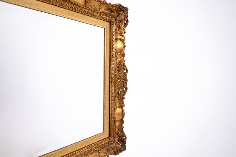 A mirror with a golden, richly carved frame.
