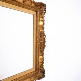 A mirror with a golden, richly carved frame.