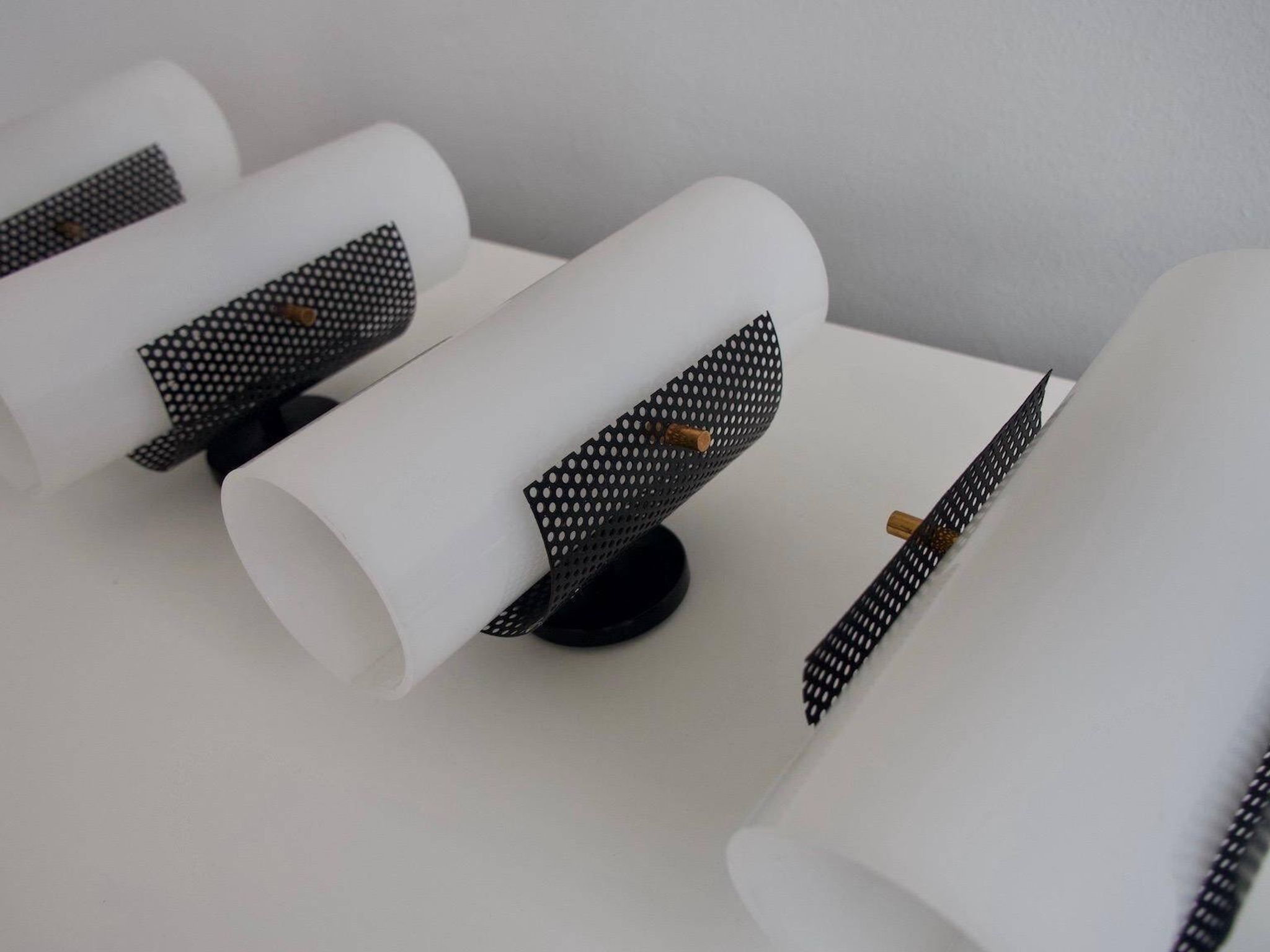 Set of four wall lights in white plexiglass and perforated black metal.