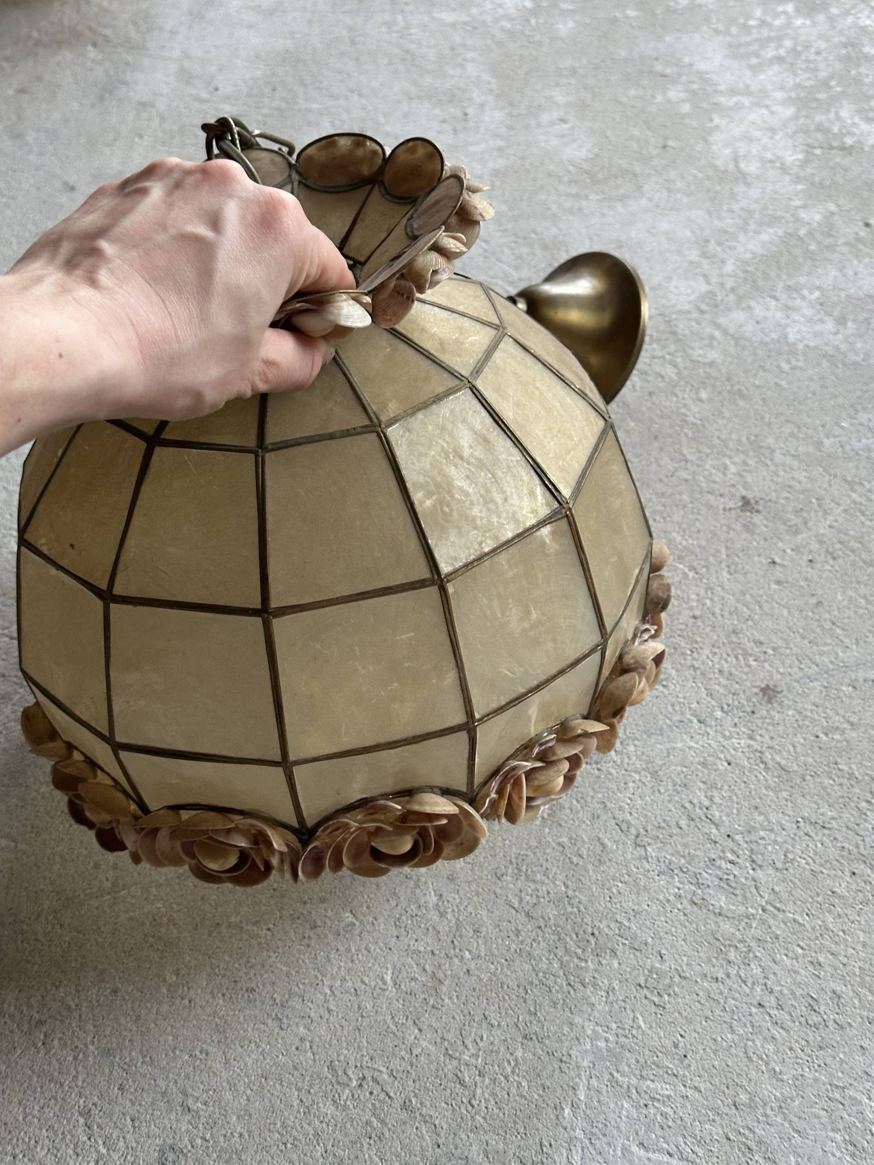 Vintage pendant light with a pearlescent shade and floral decoration.