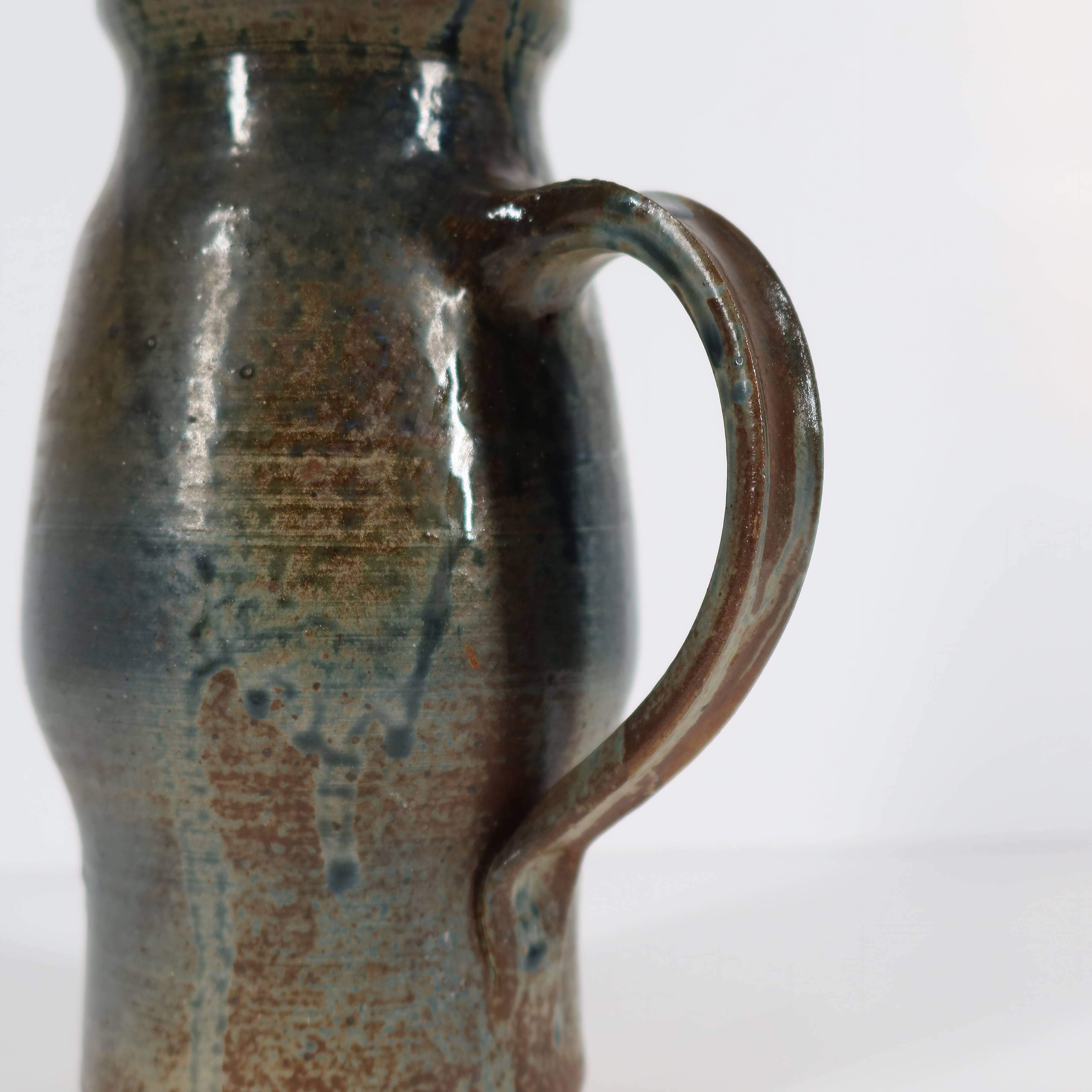 Handcrafted stoneware pitcher with blue-green hues, signed piece