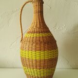 Vintage glass bottle covered with hand-woven wicker and scoubidou, with a handle