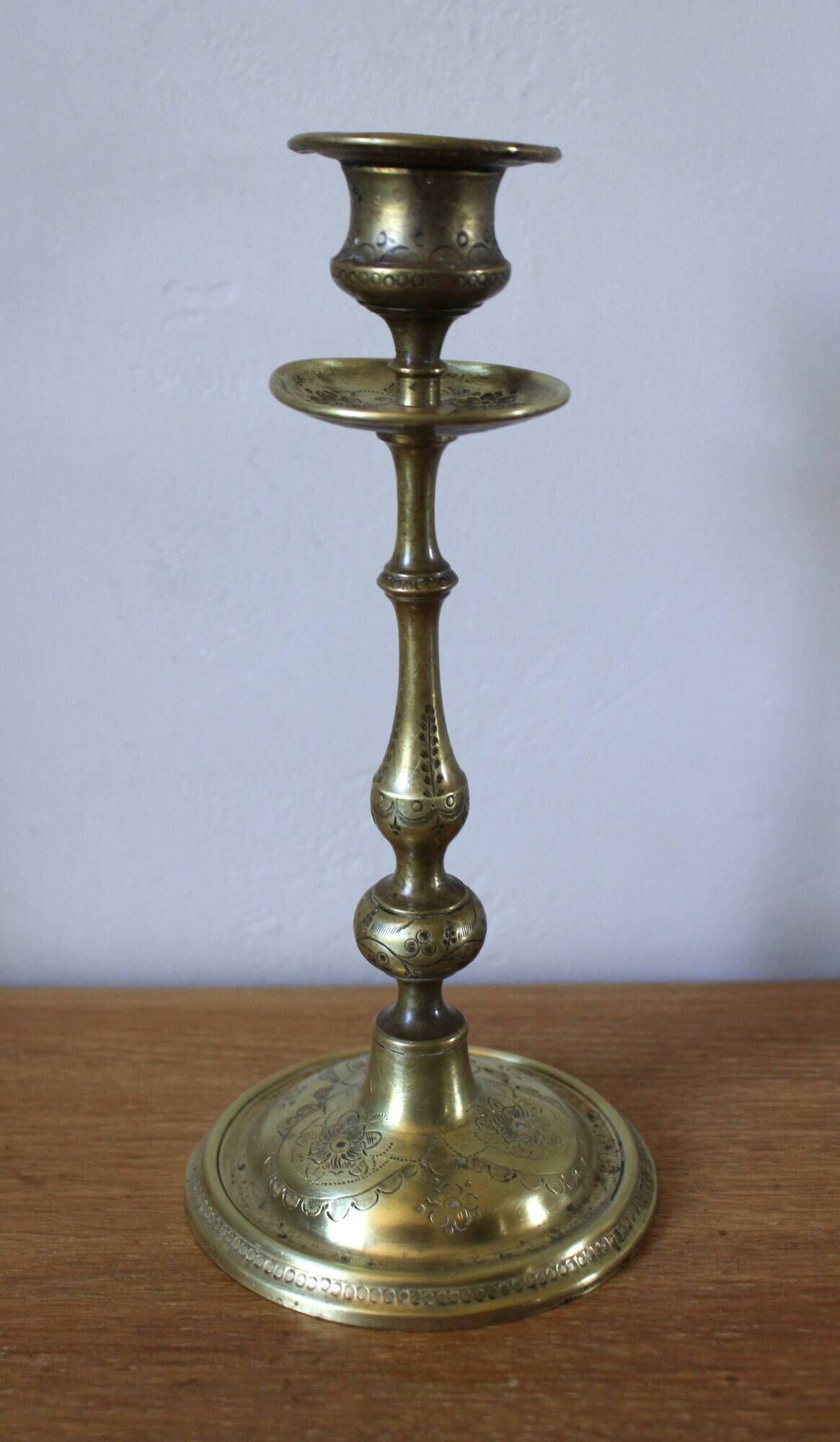 Brass candle holder with flowers and round shape.