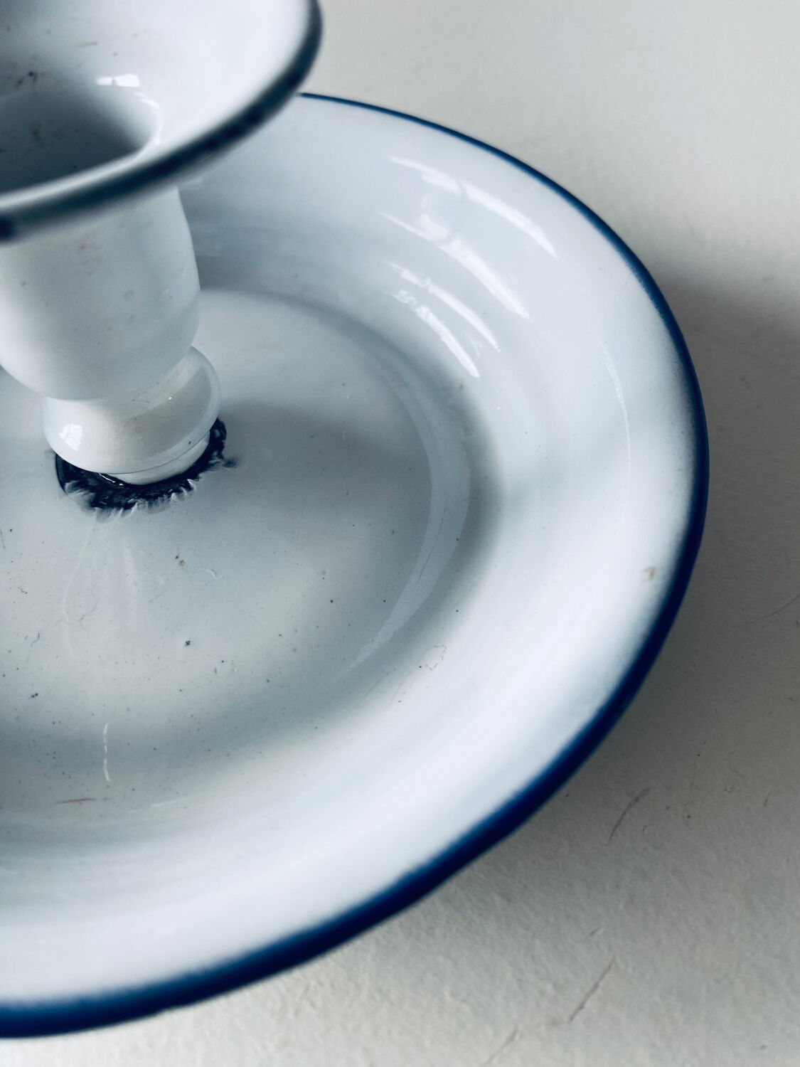 Old candle holder in white enameled metal