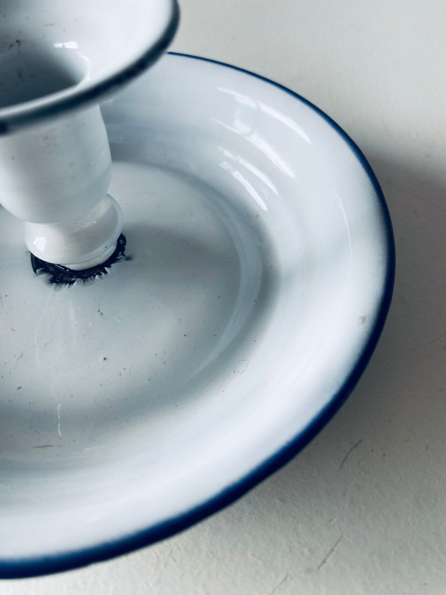 Old candle holder in white enameled metal