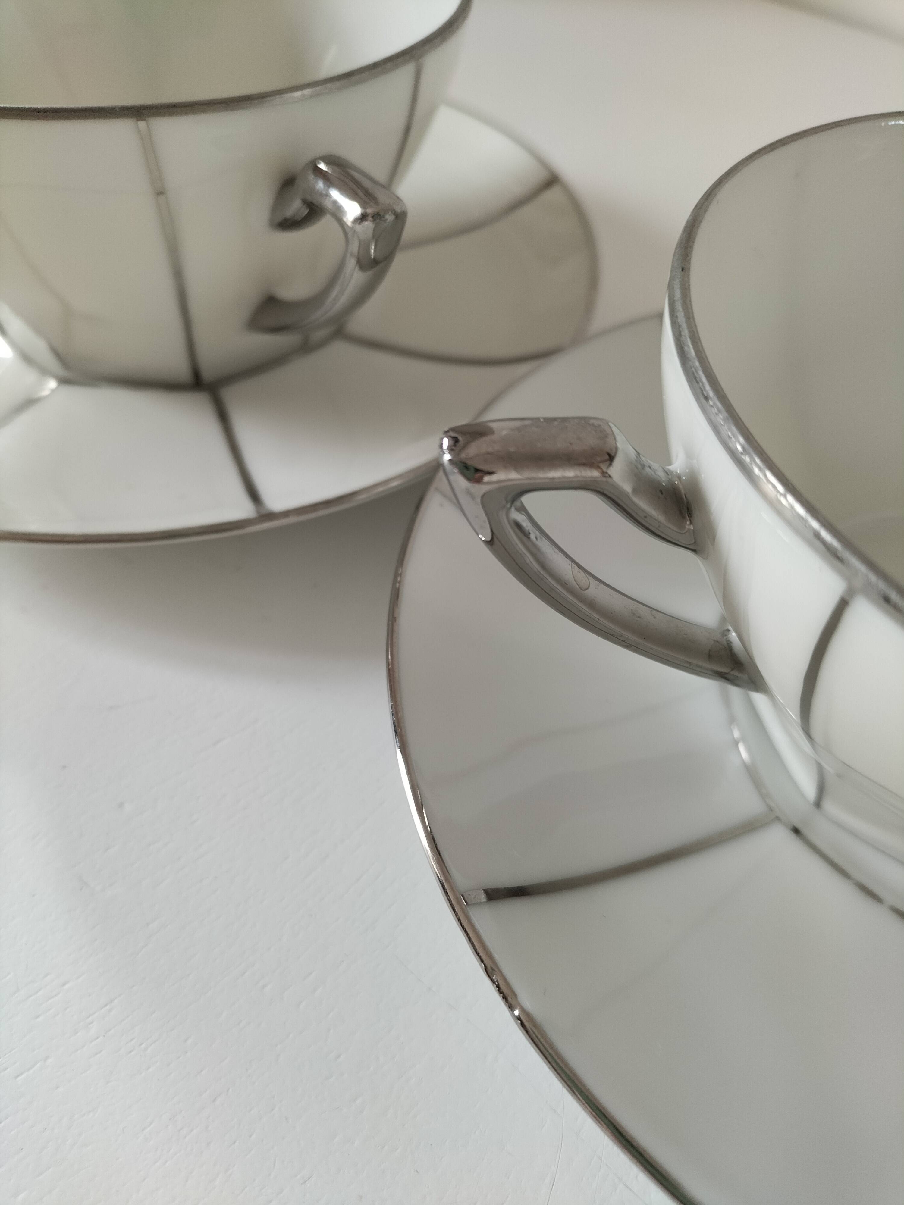 Two Art Deco porcelain cups and saucers with silver trim.