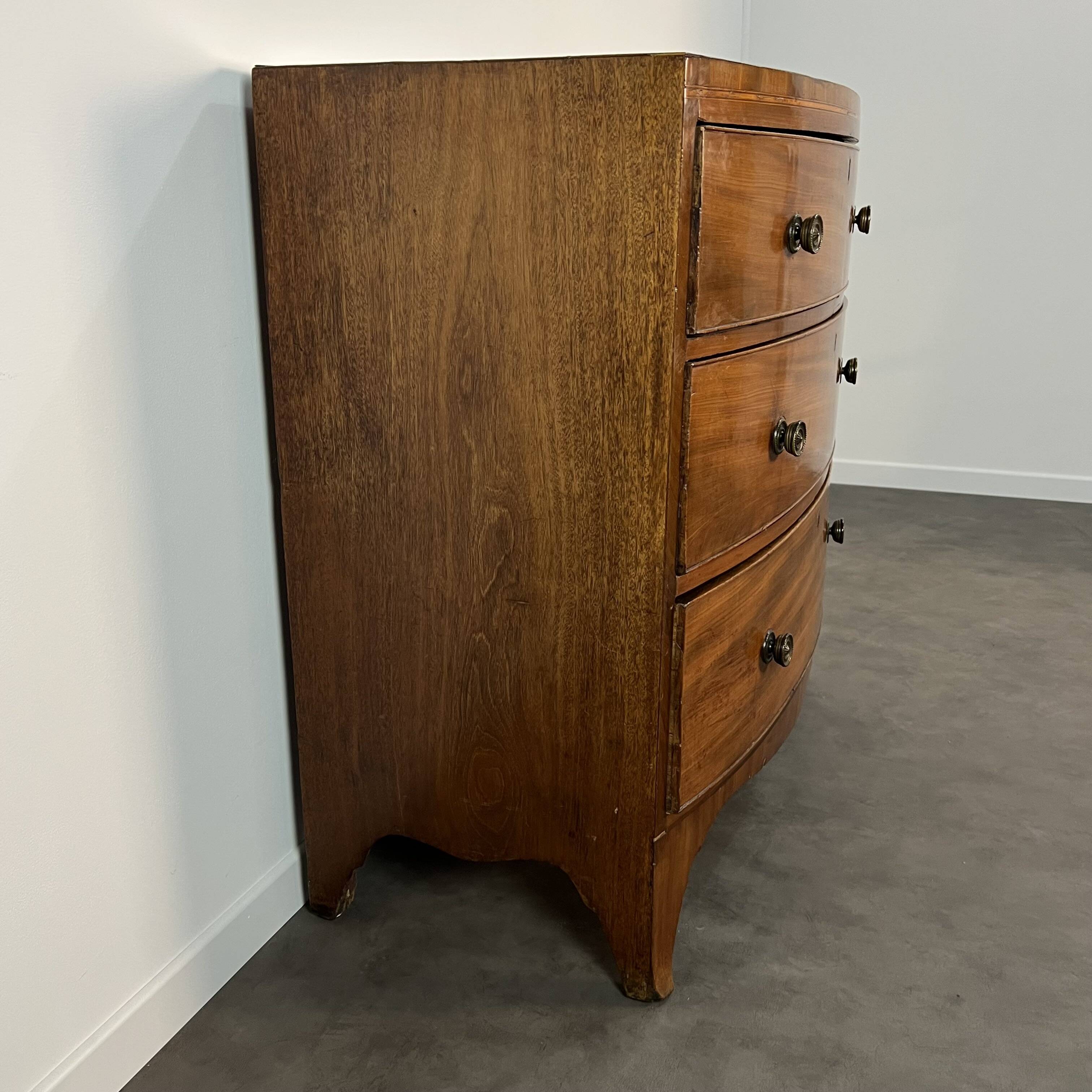 English commode from the George III Regency period, bombe shape in mahogany veneer.