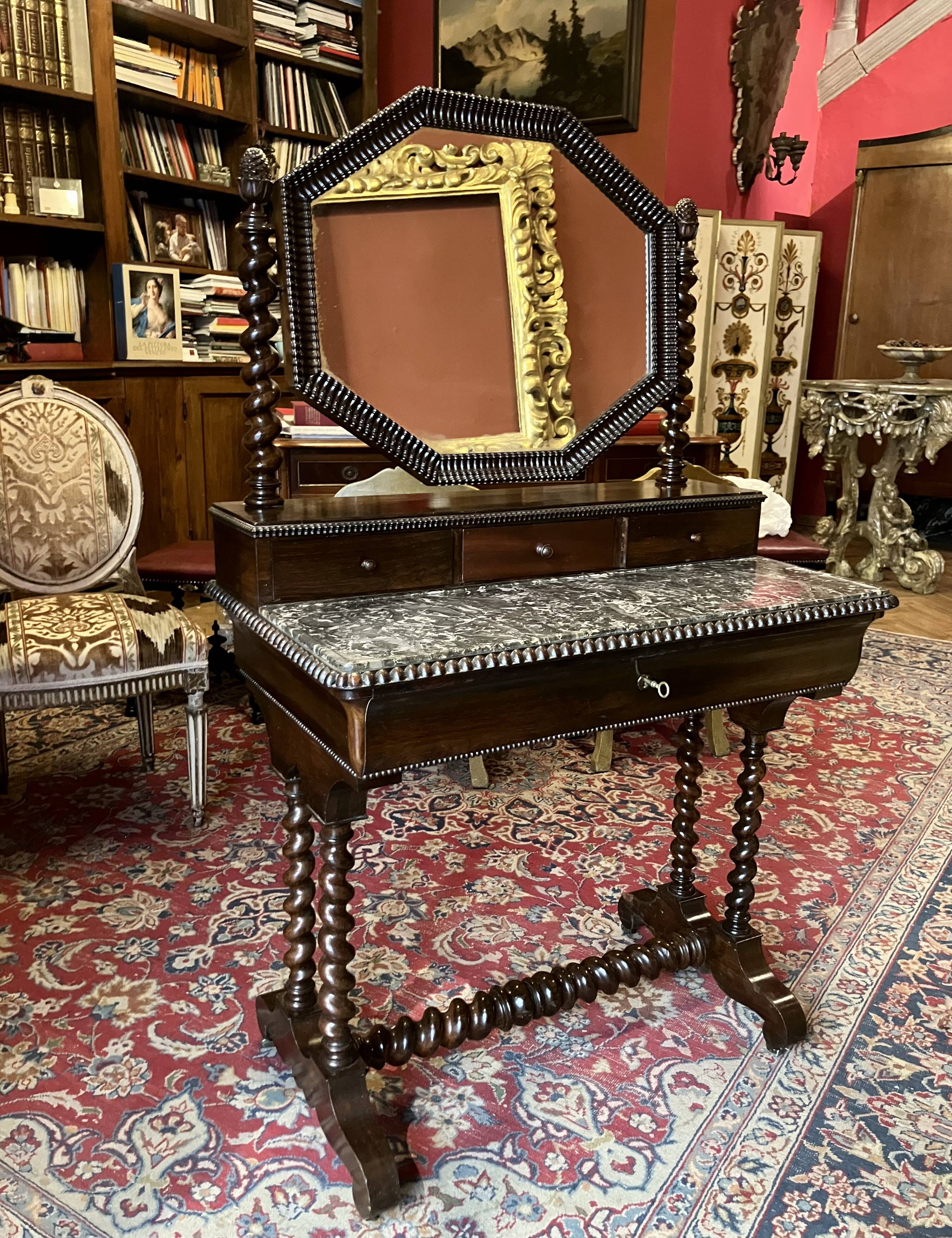 Antique English mahogany dressing table with carved details, black marble, and mirror.