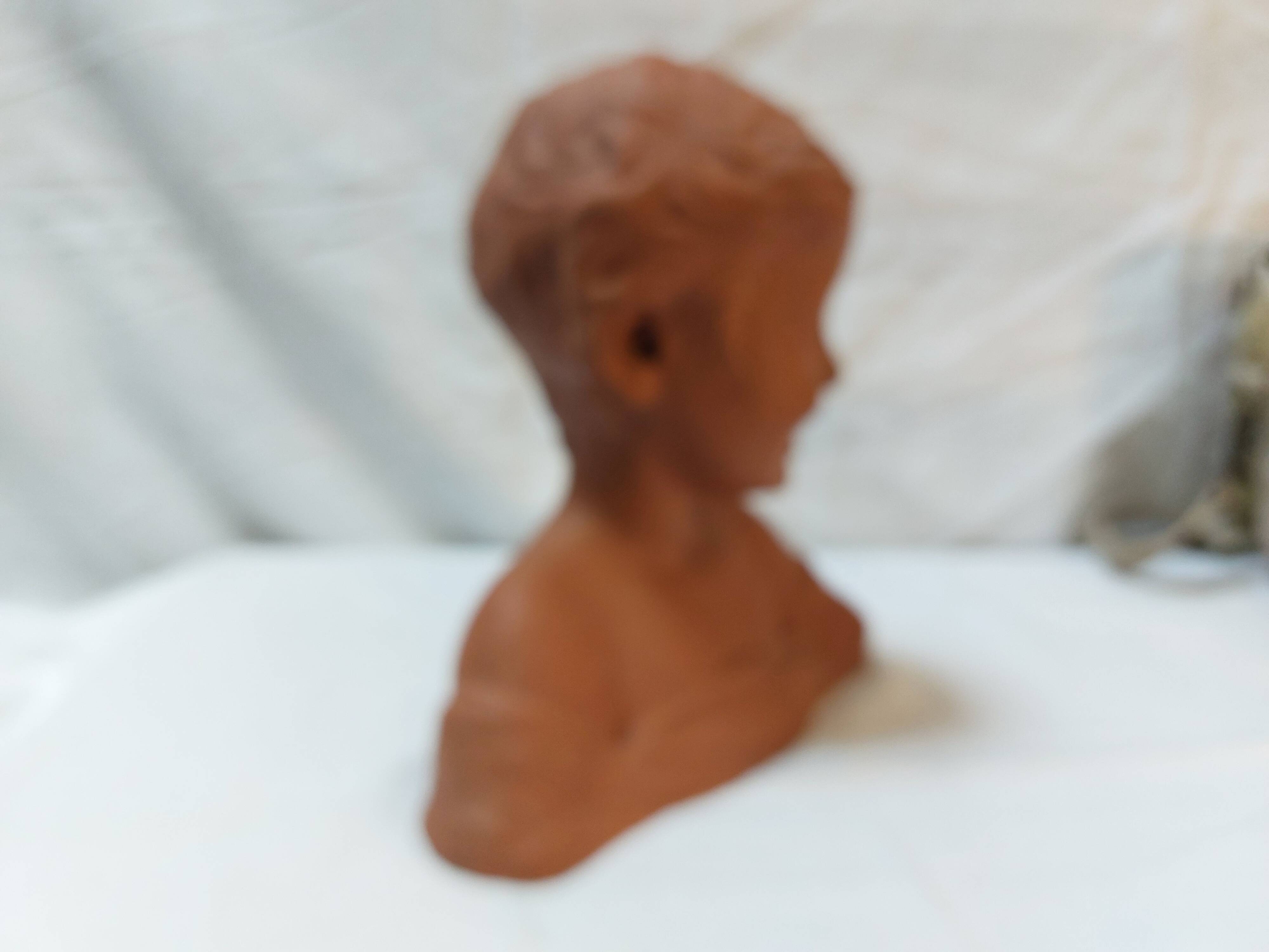 Terracotta bust of a smiling little boy.