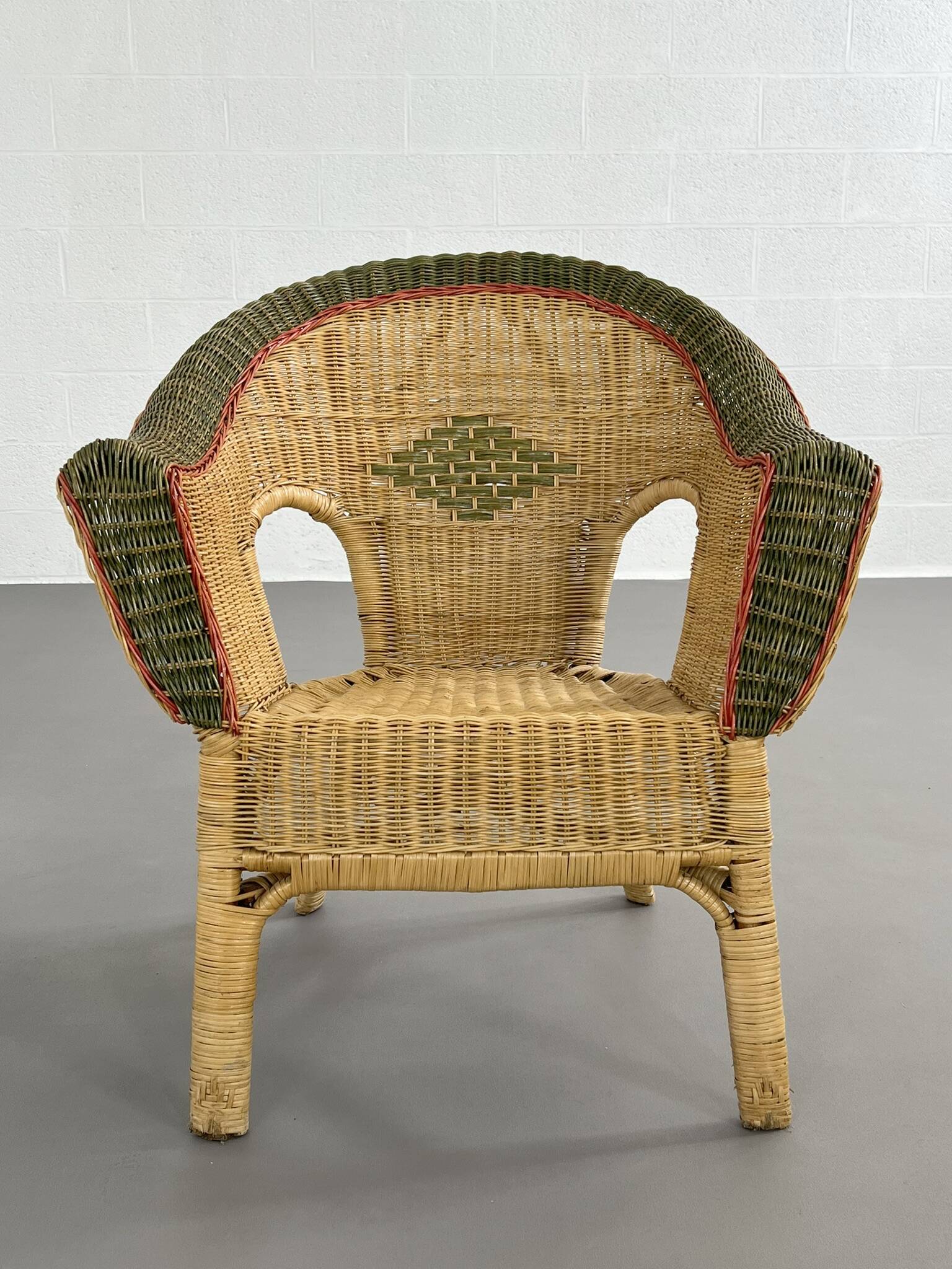 Cabriolet style armchair in rattan, wicker and green and red edging