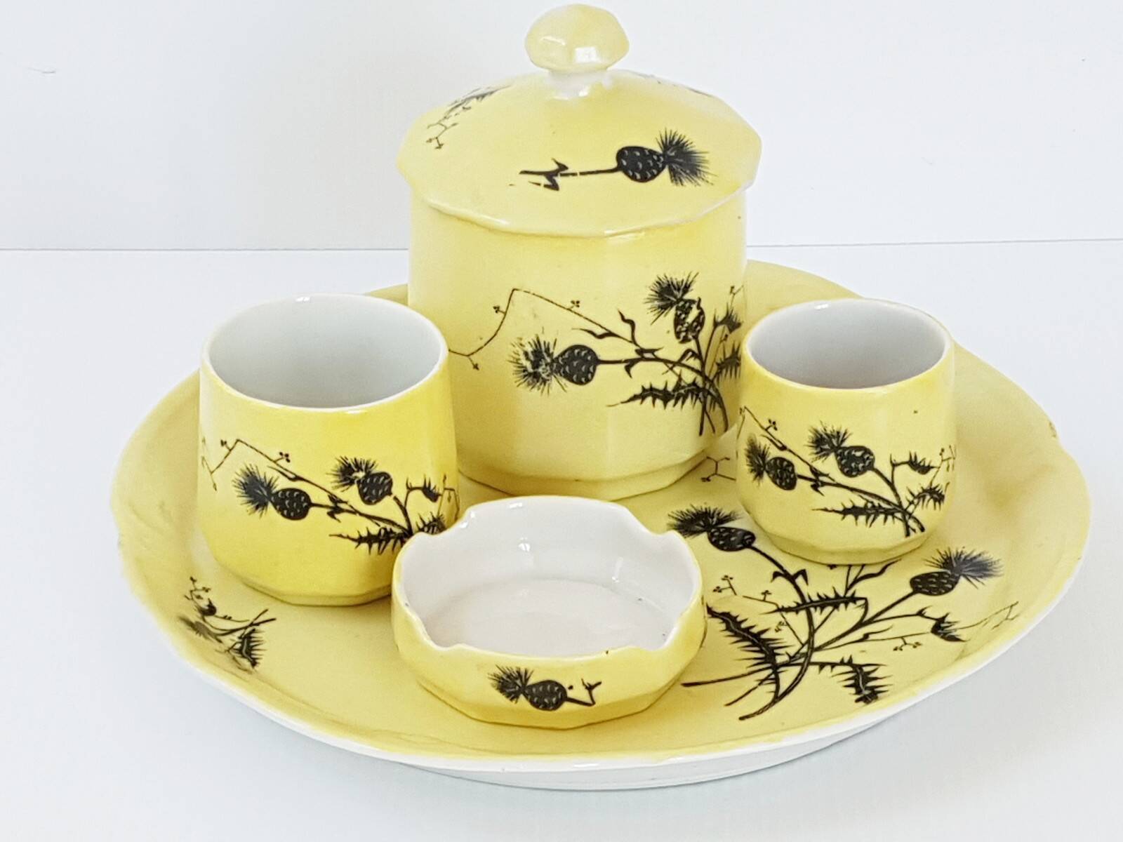 A yellow Art Deco ceramic tobacco service decorated with thistles from the 1920s to 1930s.