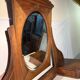Antique carved wooden dressing table with marble and tilting oval mirror.