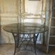 Round table with metal legs and smoked glass.