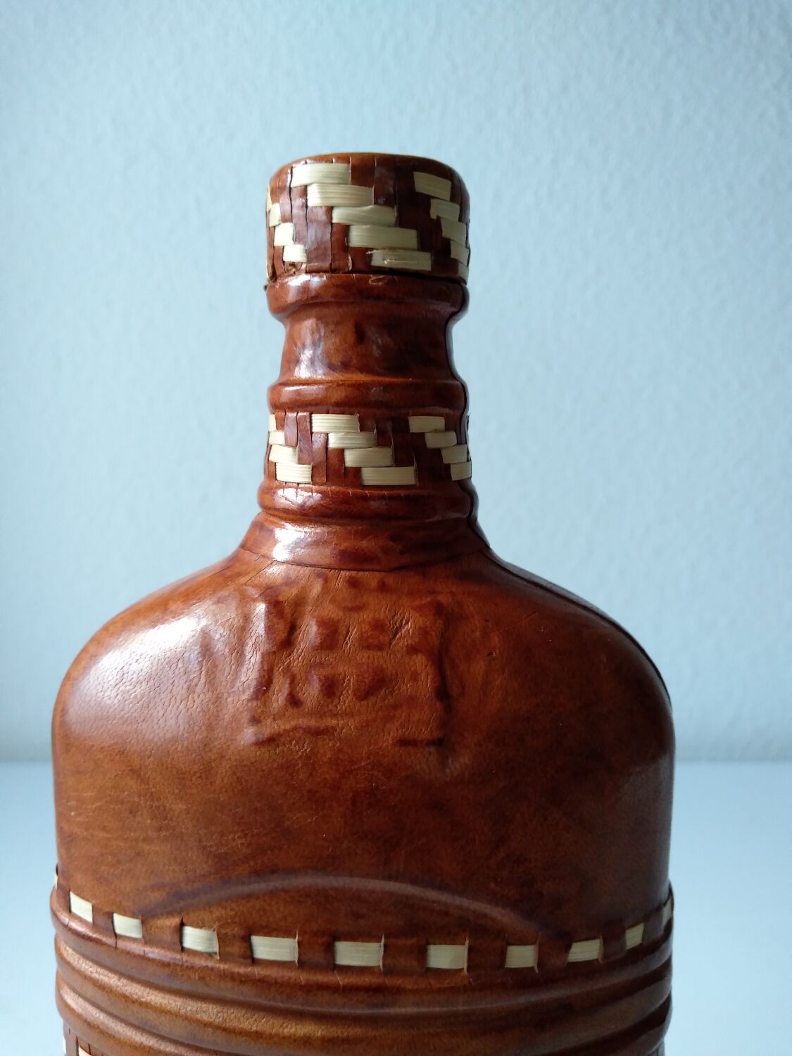 Vintage glass bottle covered with light brown leather and wicker