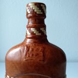 Vintage glass bottle covered with light brown leather and wicker