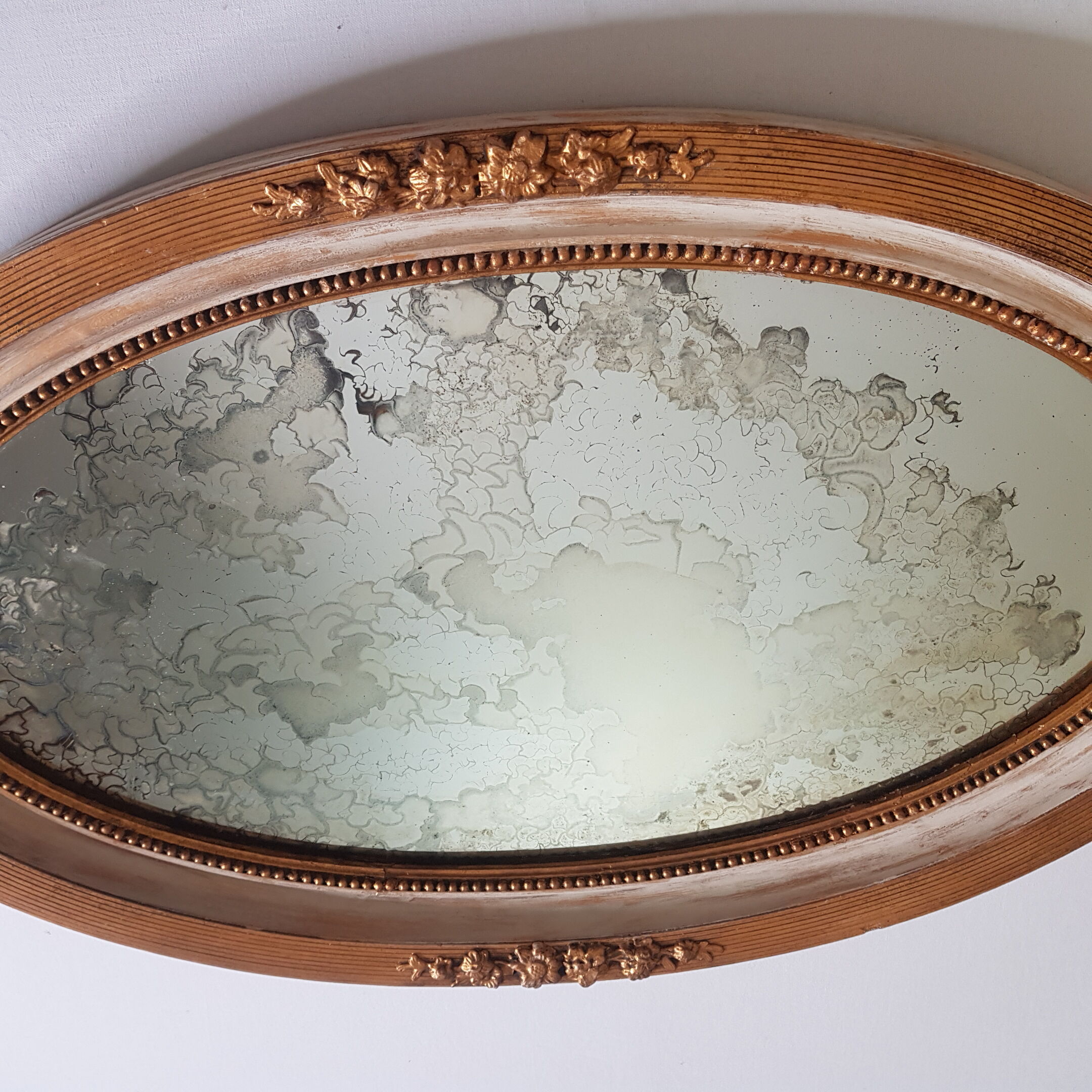Large oval mirror with bevelled ice in stucque and wood decorated with flowers