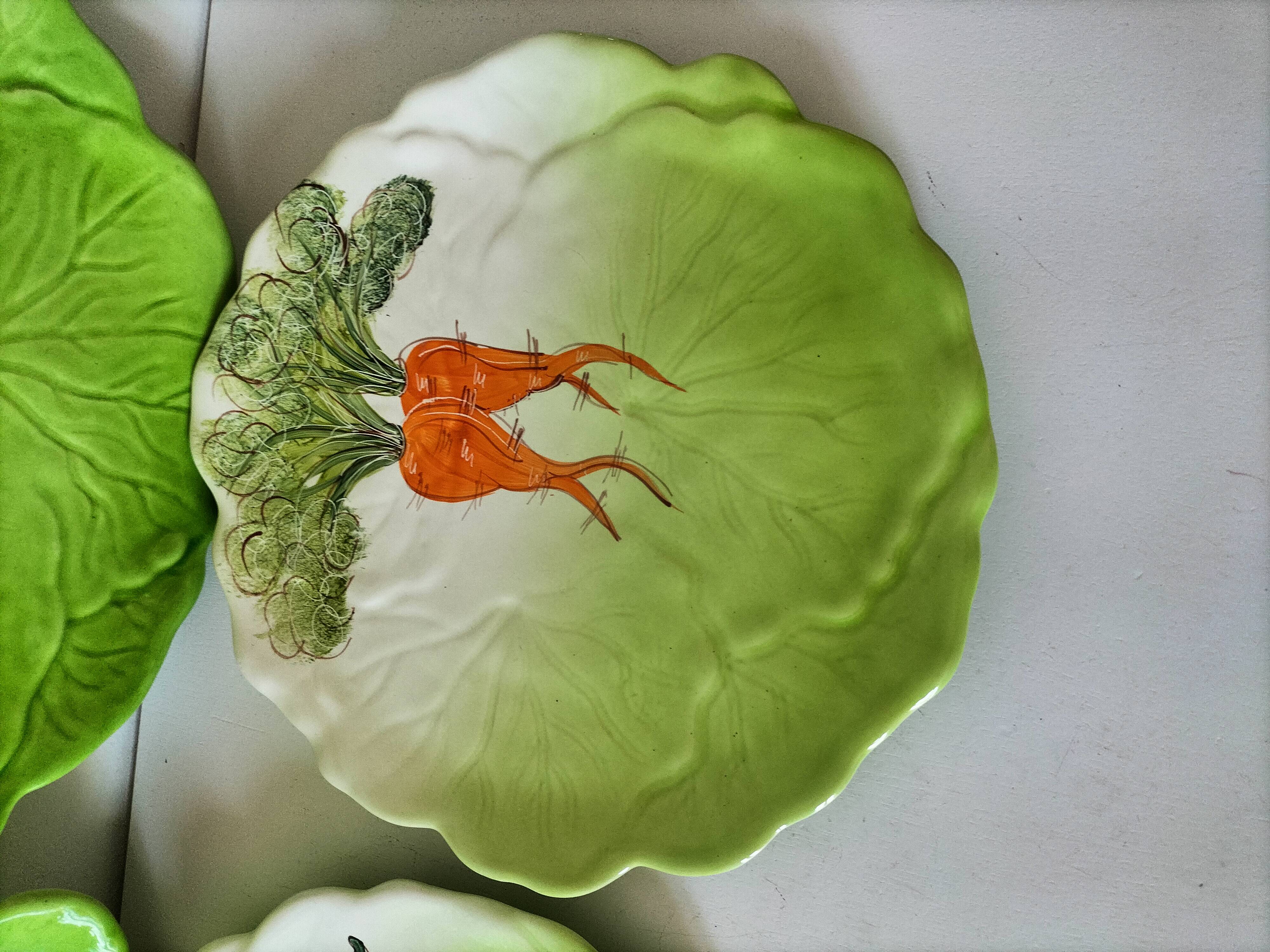 4 hand-decorated earthenware plates with vegetable and green leaf designs.