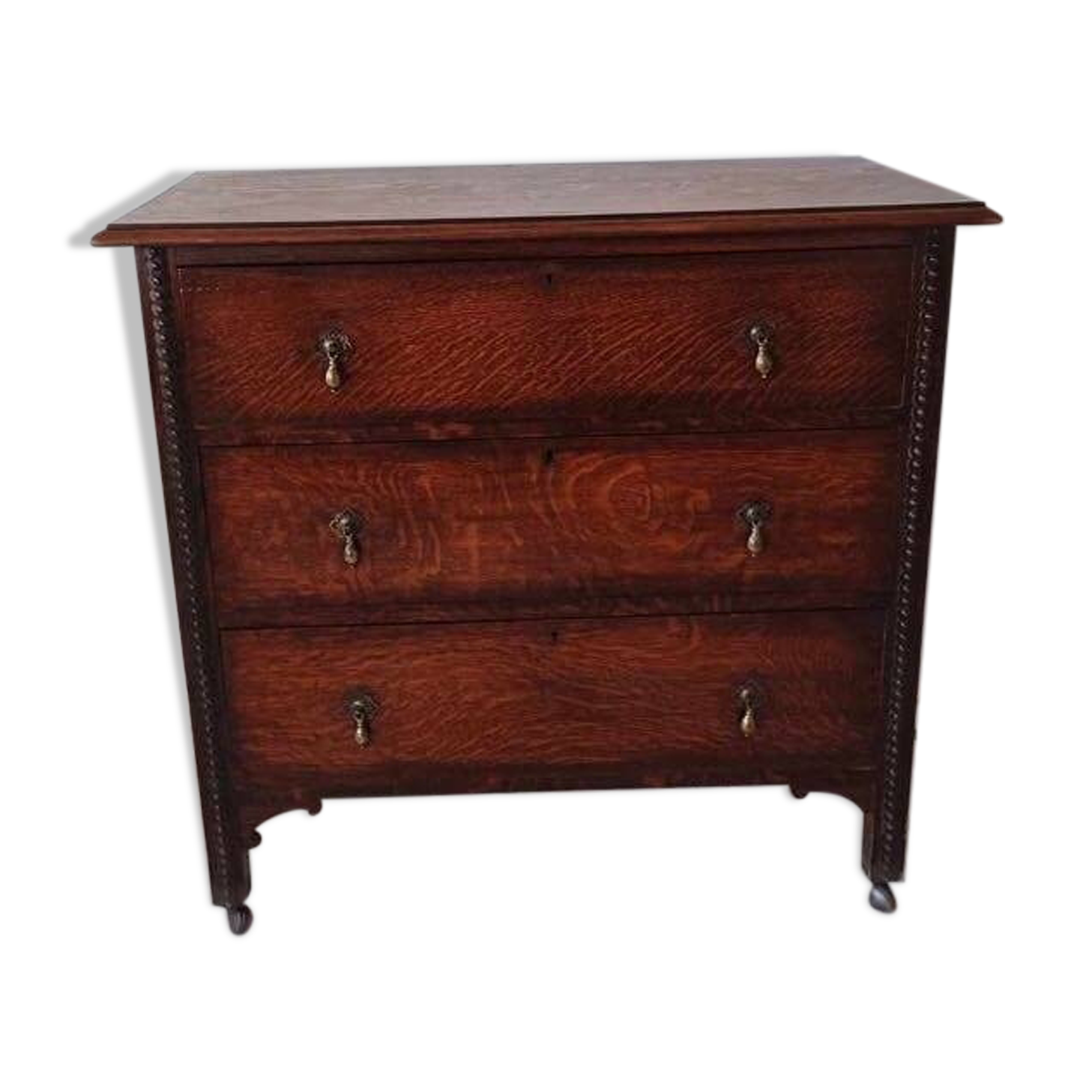 Antique oak chest of drawers on castors with brass handles and carved details