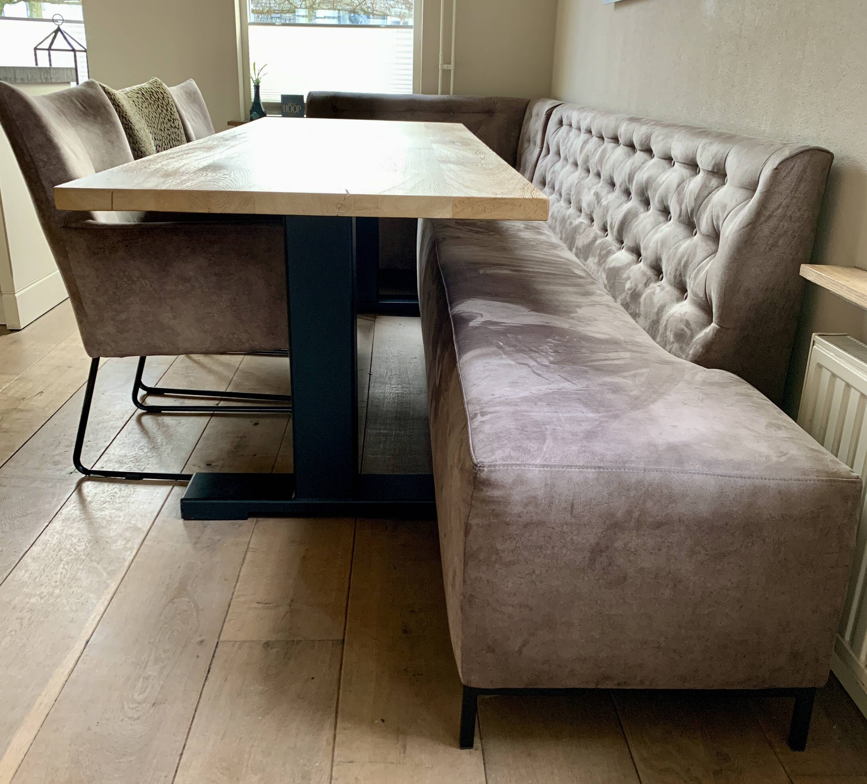 Dining table made of wood with three leather seats and a long leather sofa.