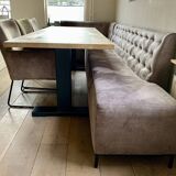 Dining table made of wood with three leather seats and a long leather sofa.