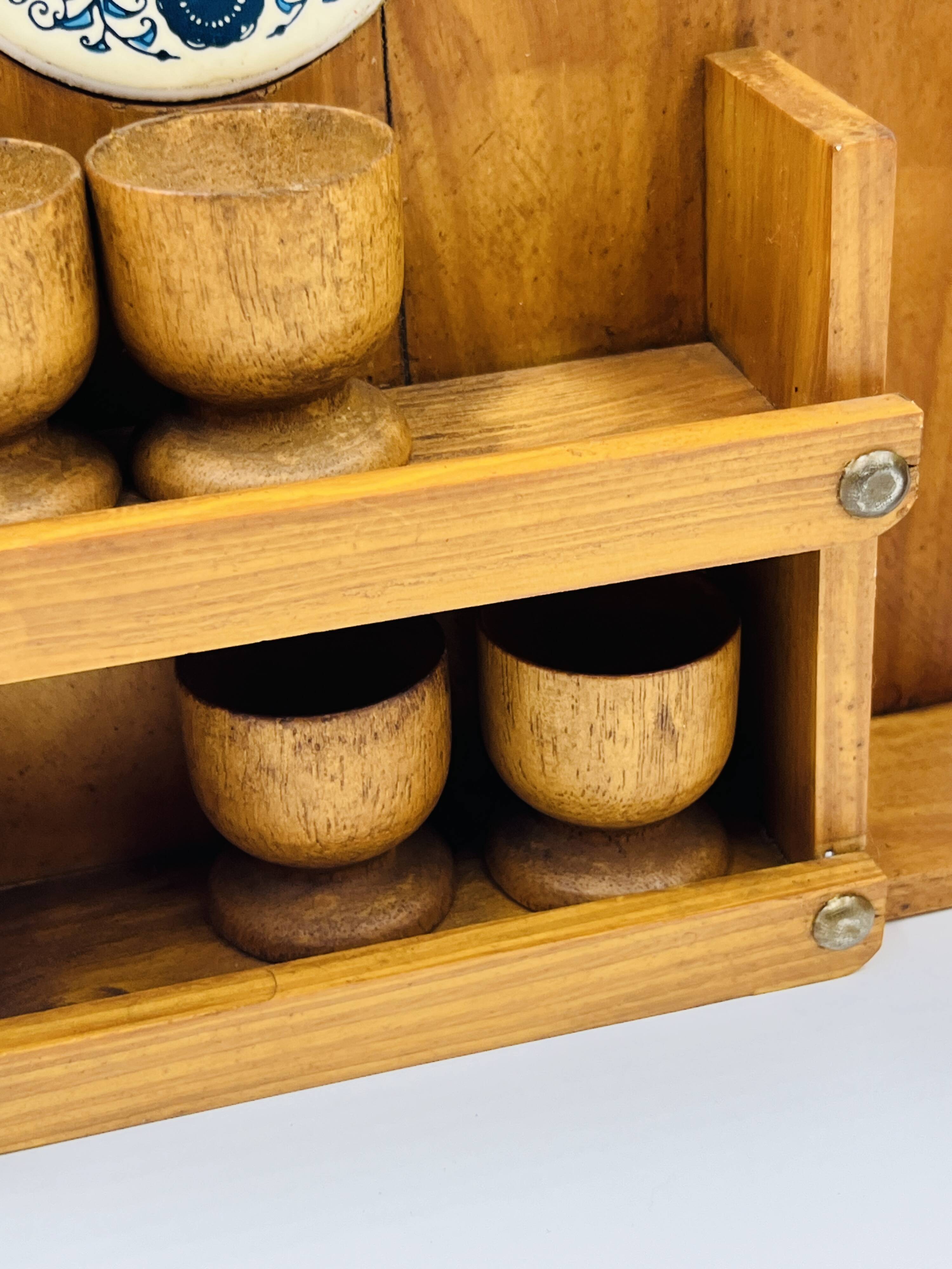 Wall-mounted egg cup holder and wooden utensil holder.