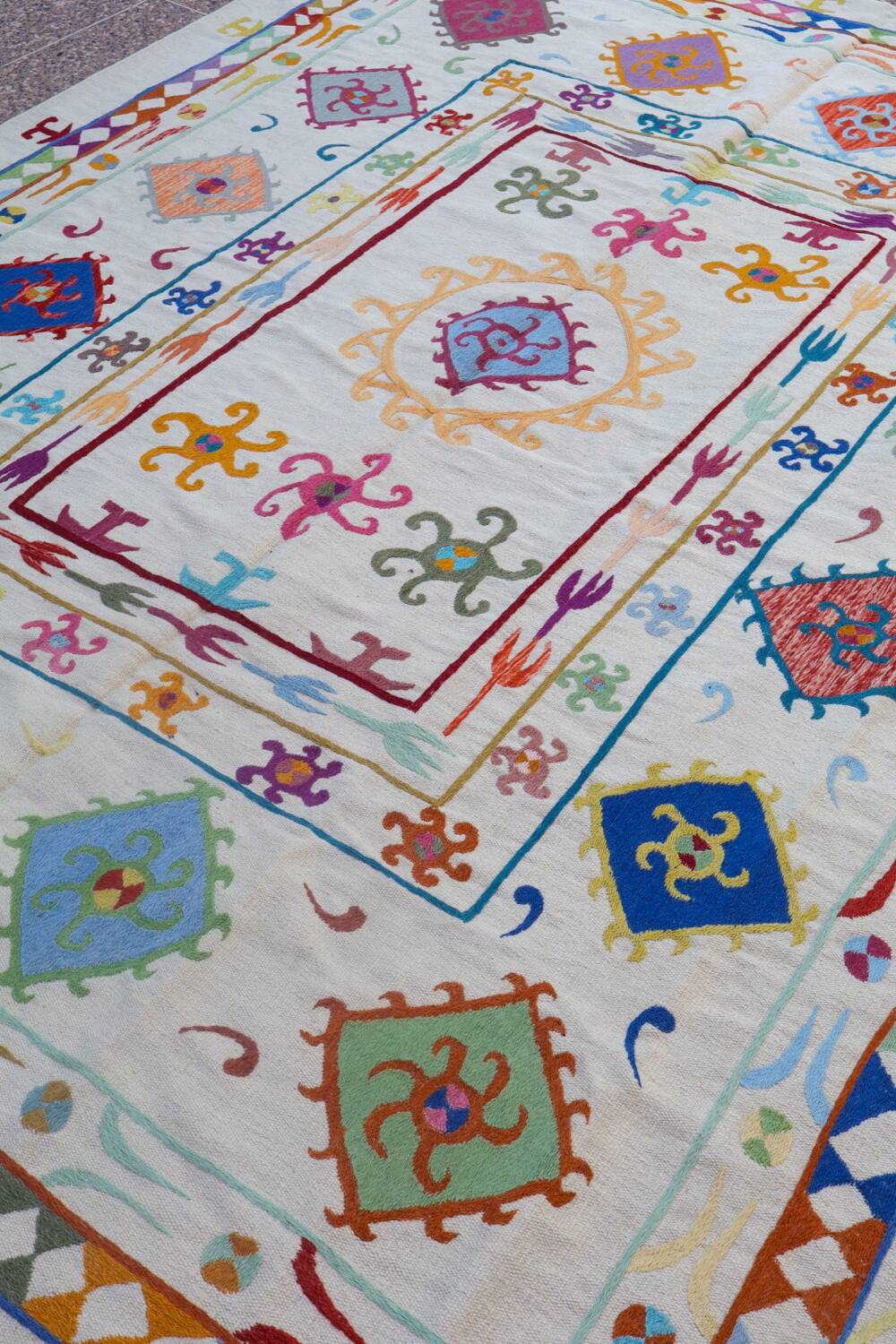 White suzani kilim rug with multi-colored embroidered patterns