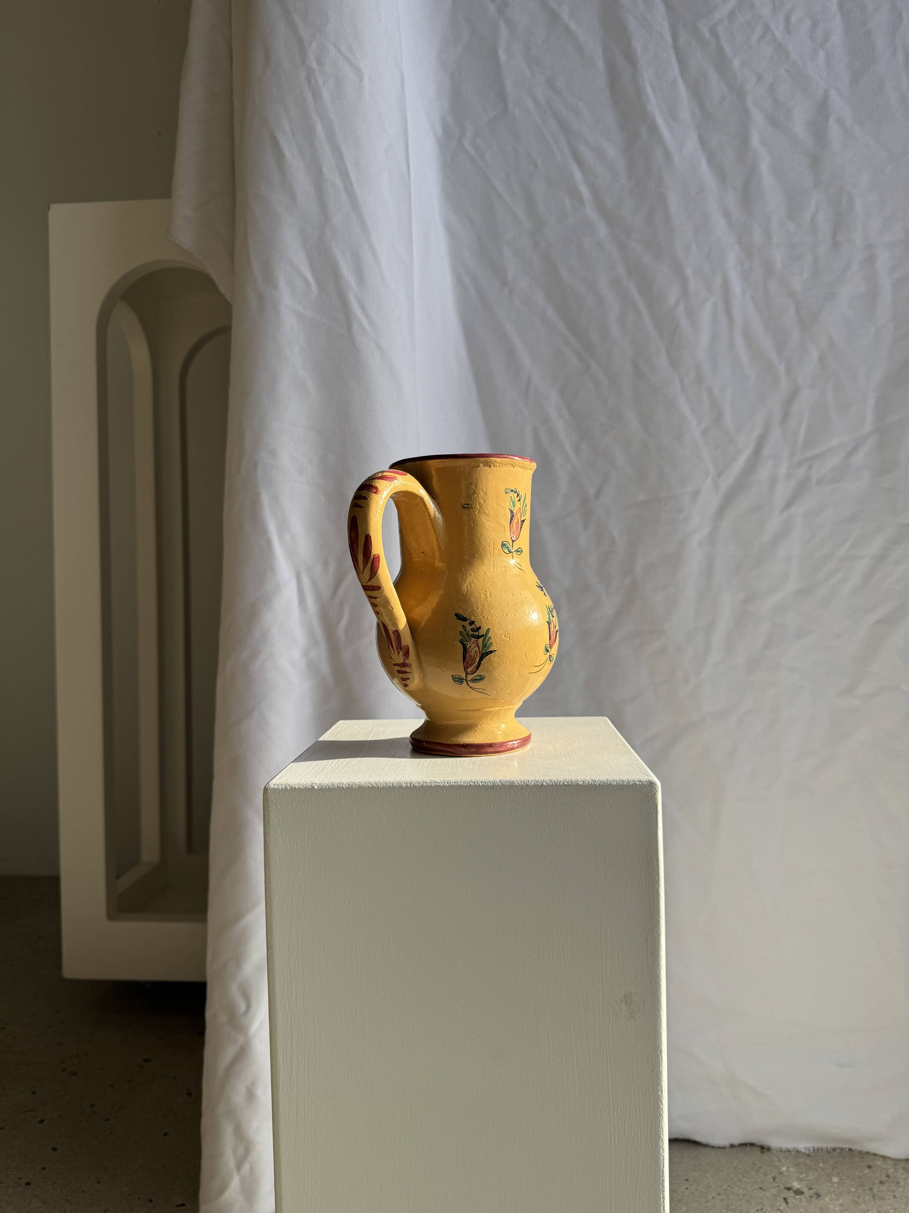 Large antique handmade ochre yellow jug with a pink flower pattern.