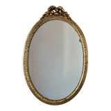 Oval mirror in gilded wood with a pediment.
