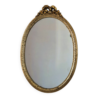 Oval mirror in gilded wood with a pediment.