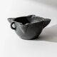 Vintage ceramic ashtray from the 1960s, black, hand-sculpted texture, organic shape.