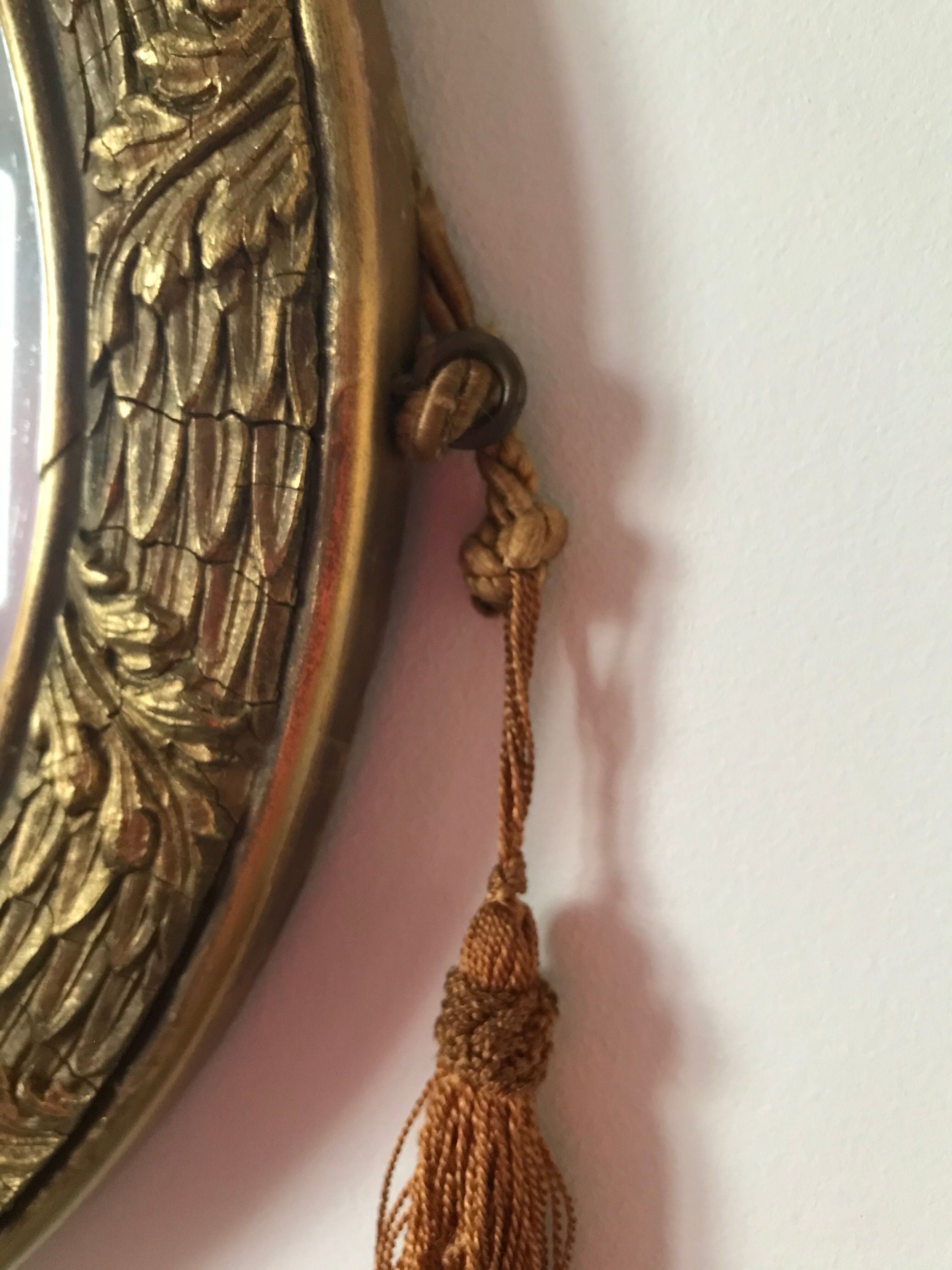 Golden oval mirror with its wooden frame and stucco on wood, nicely cracked by time