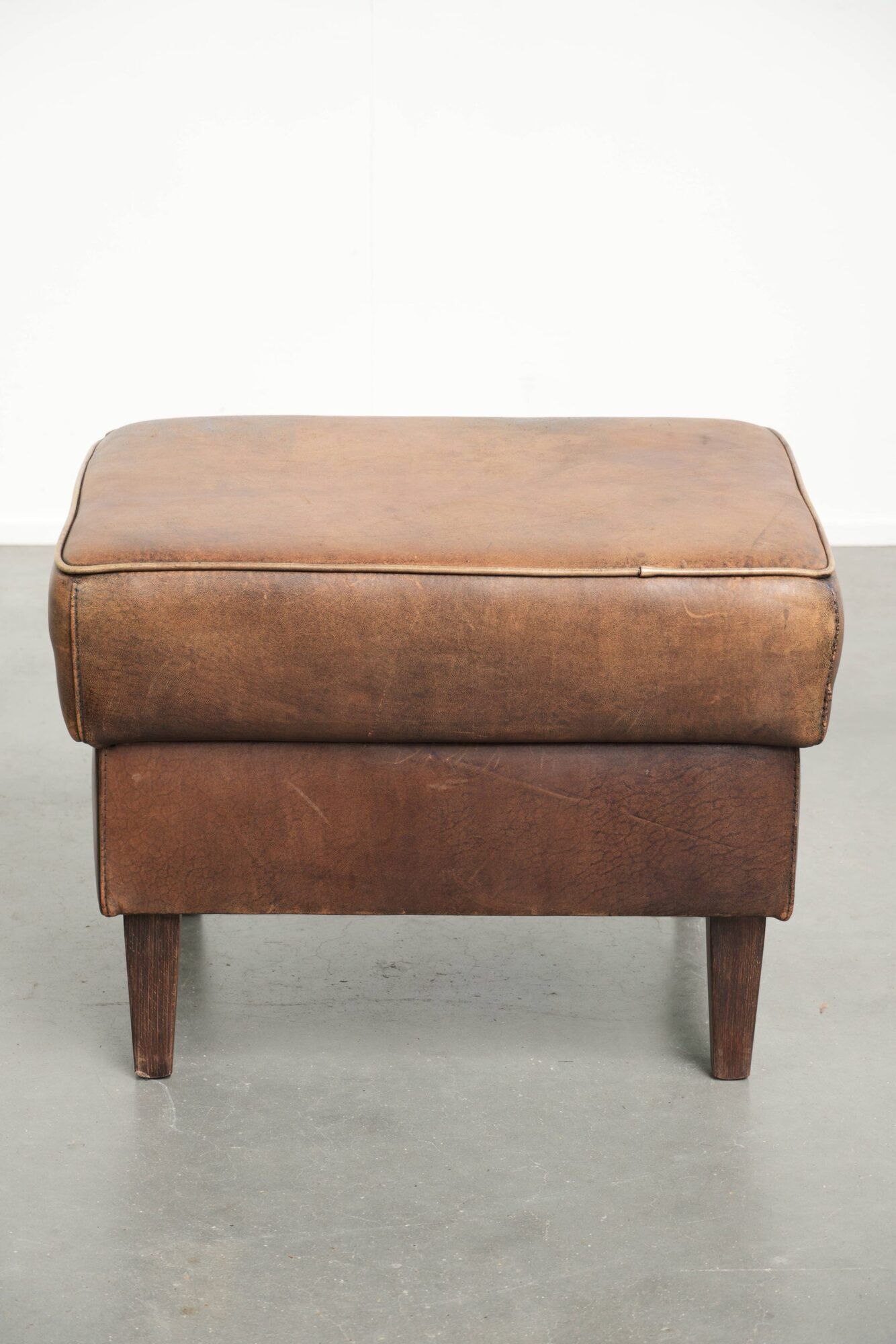 Set of a sheepskin armchair and ottoman finished with matching piping