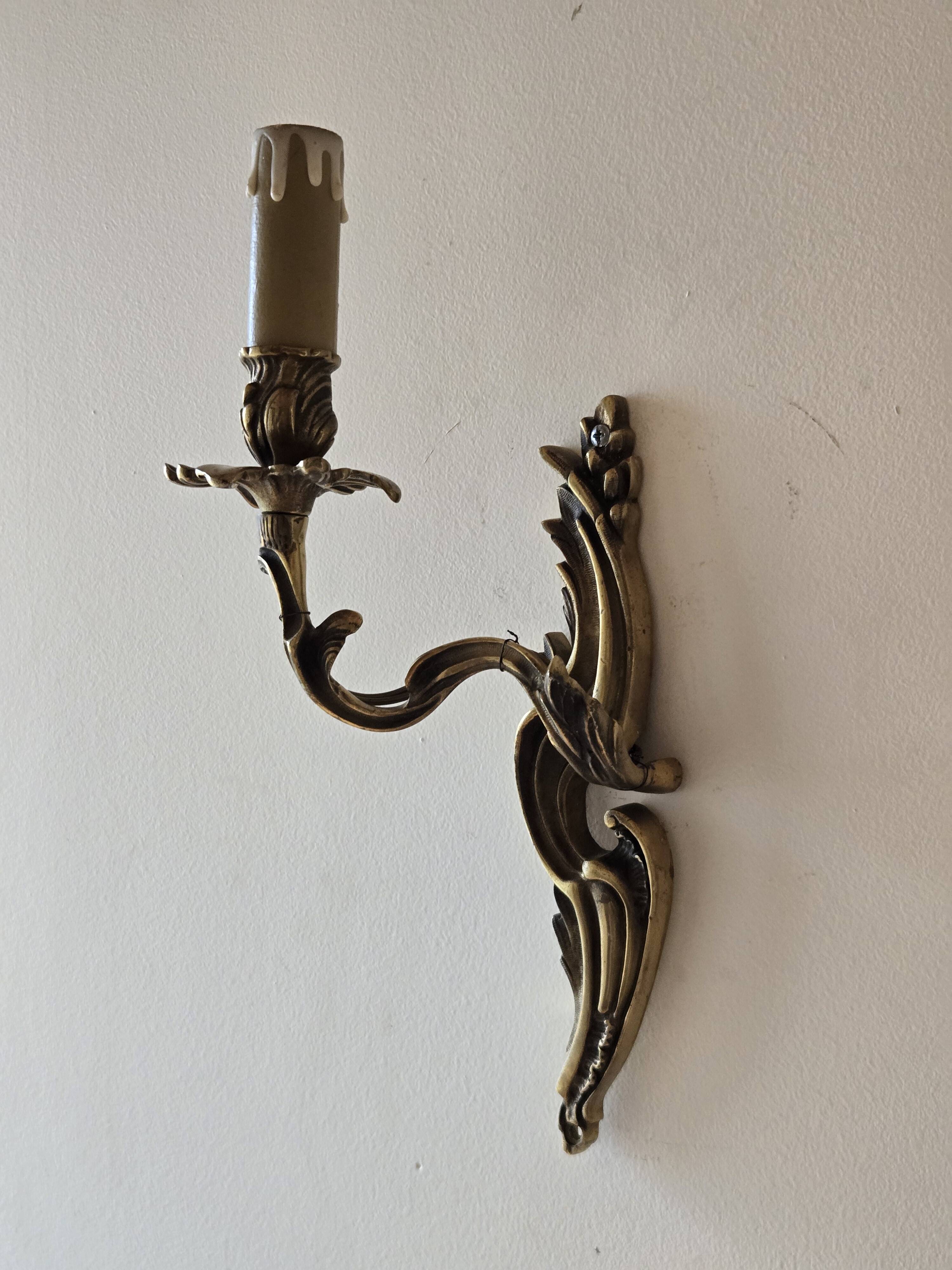 Pair of symmetrical gold wall sconces in baroque style made of bronze.